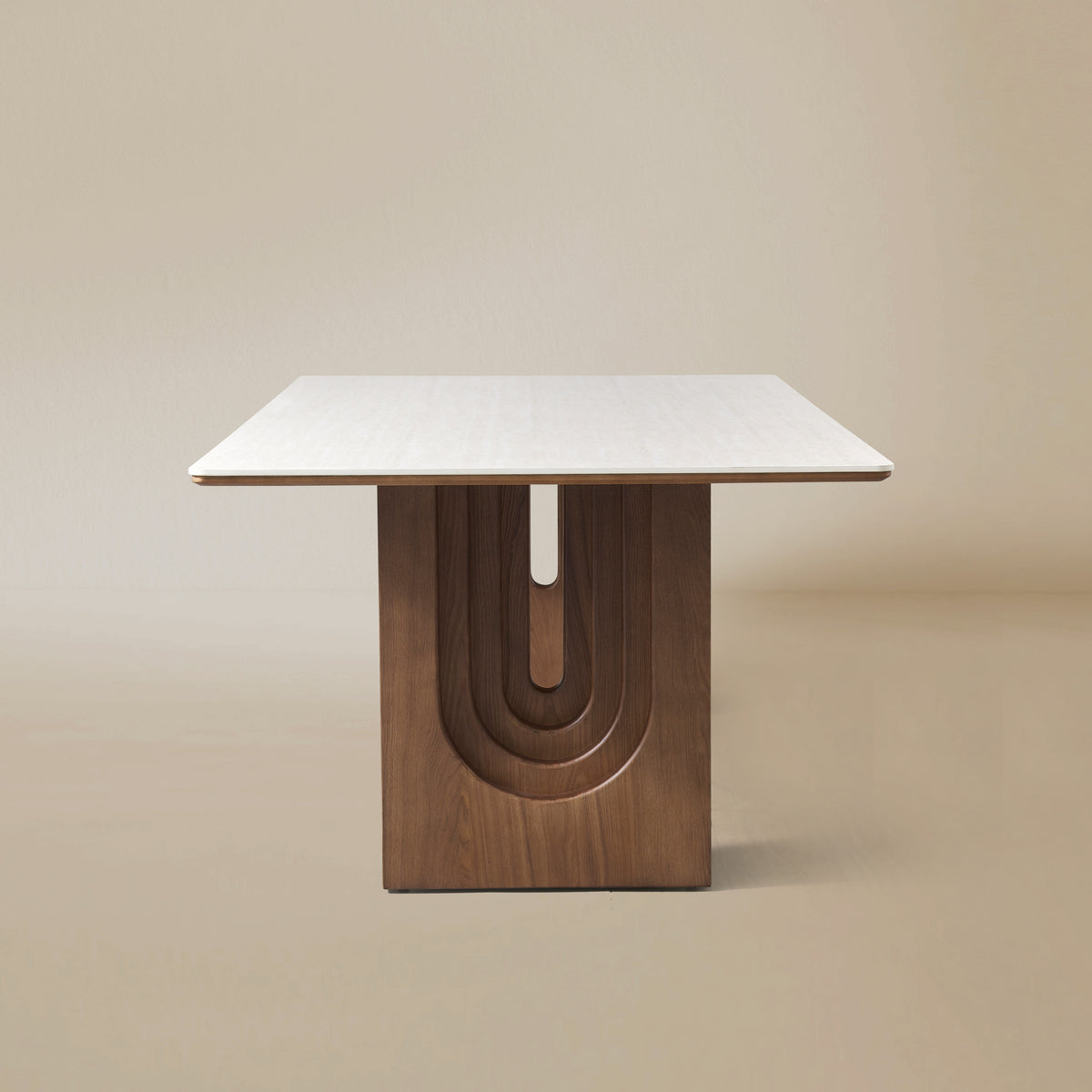 Side view of the Arcadian Dining Table with a white travertine top and walnut wooden legs on a beige background