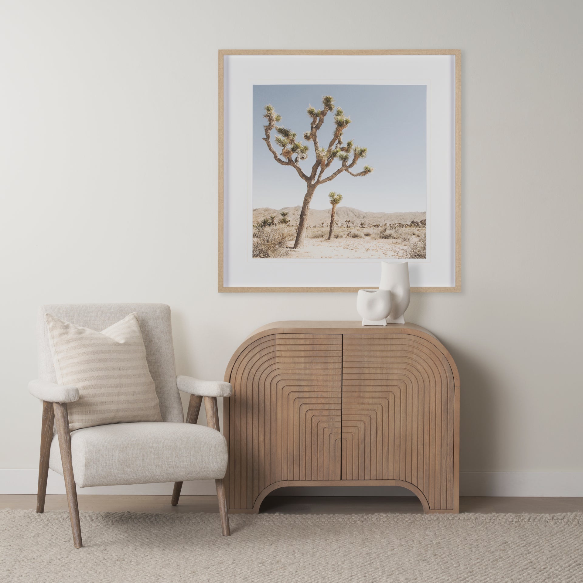 Arco fluted cabinet styled in a neutral living room next to a beige armchair and desert artwork.