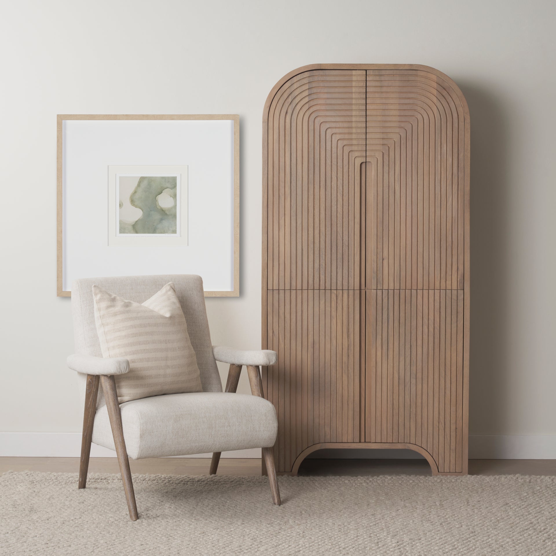 Tall Arco fluted cabinet styled in a neutral living room next to a beige armchair and framed artwork.