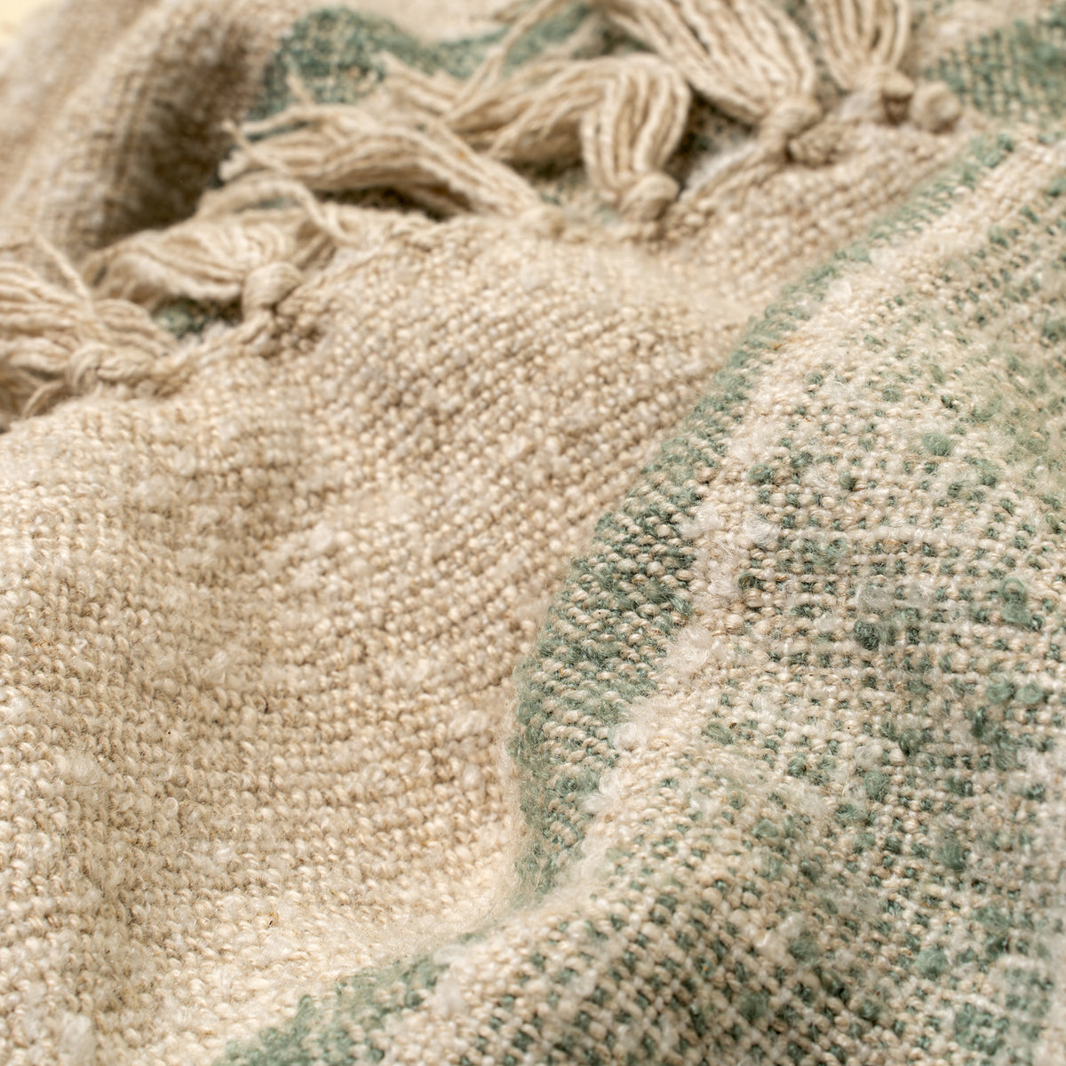 Close-up of textured fabric with tassels and a patterned border.