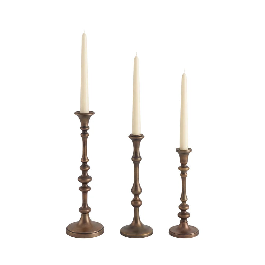 Caldria set of three antique brass-finished candle holders shown with ivory taper candles against a white background.