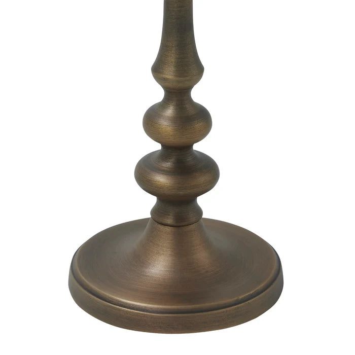Close-up of a Caldria candle holder showing its round base, sculpted cast aluminium stem, and antique brass finish.