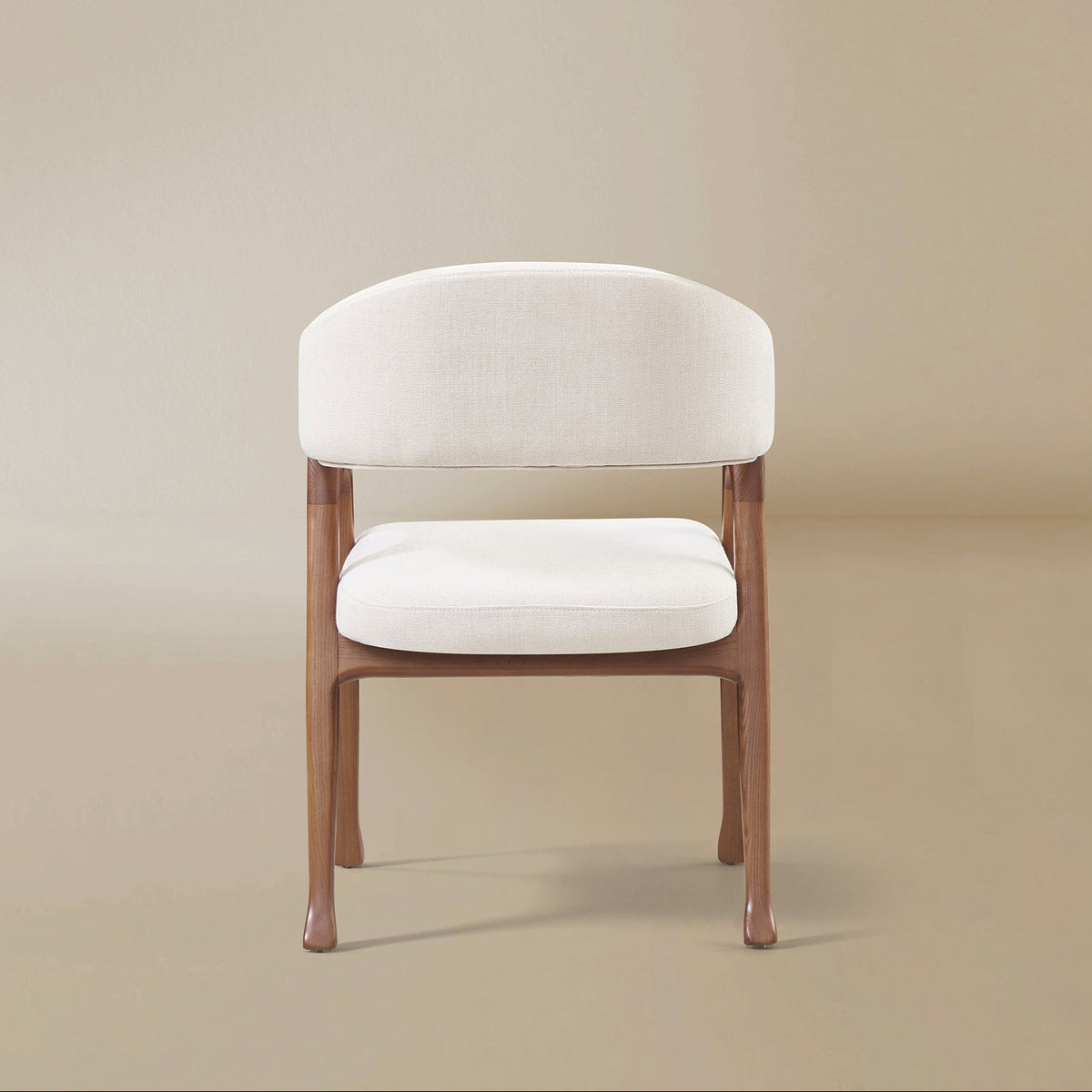 Back view of the Calira linen dining chair showing its curved upholstered backrest, open gap and ash wood veneer legs