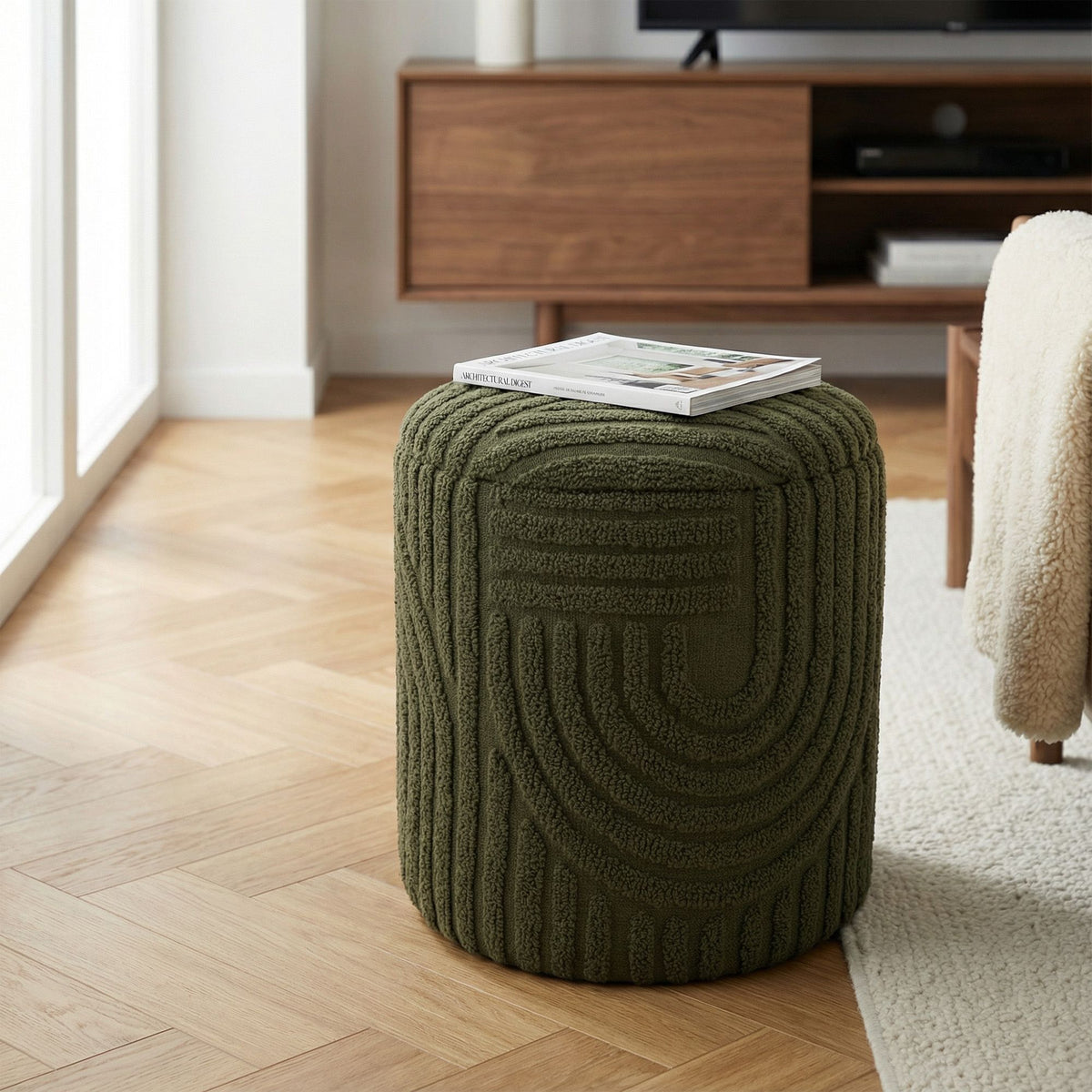 Green textured ottoman with a magazine on top in a living room setting.