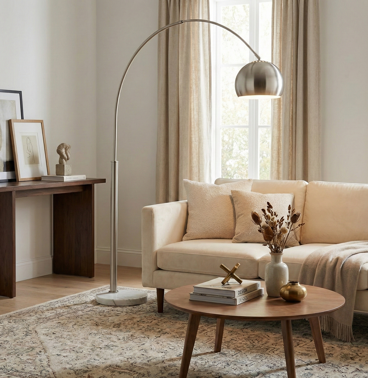 Cassia chrome arc floor lamp styled in a bright modern living room, providing overhead lighting for a sectional sofa.