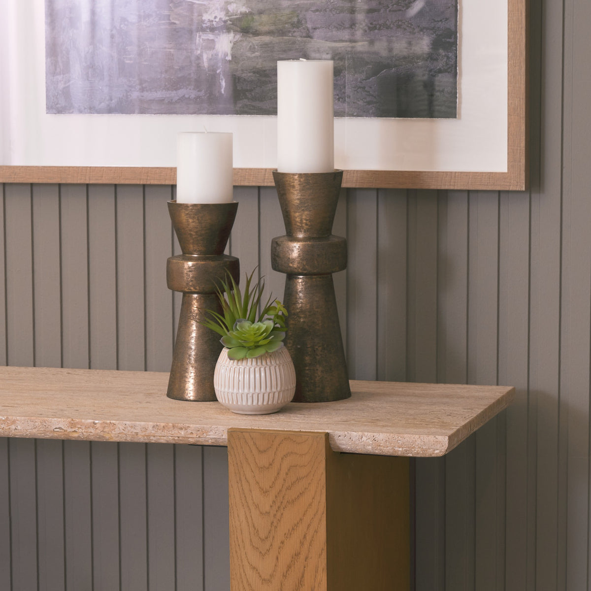 Lifestyle detail of the Cavelle Travertine & Oak Console Table with candles and a small planter arranged on the travertine surface.