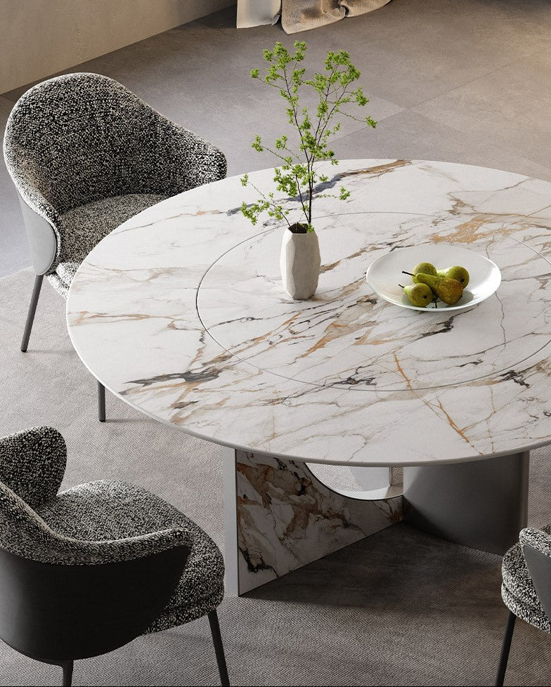 Celestia Elegance round dining table with marble-patterned sintered stone top and stainless steel base, decorated with vase and fruit bowl