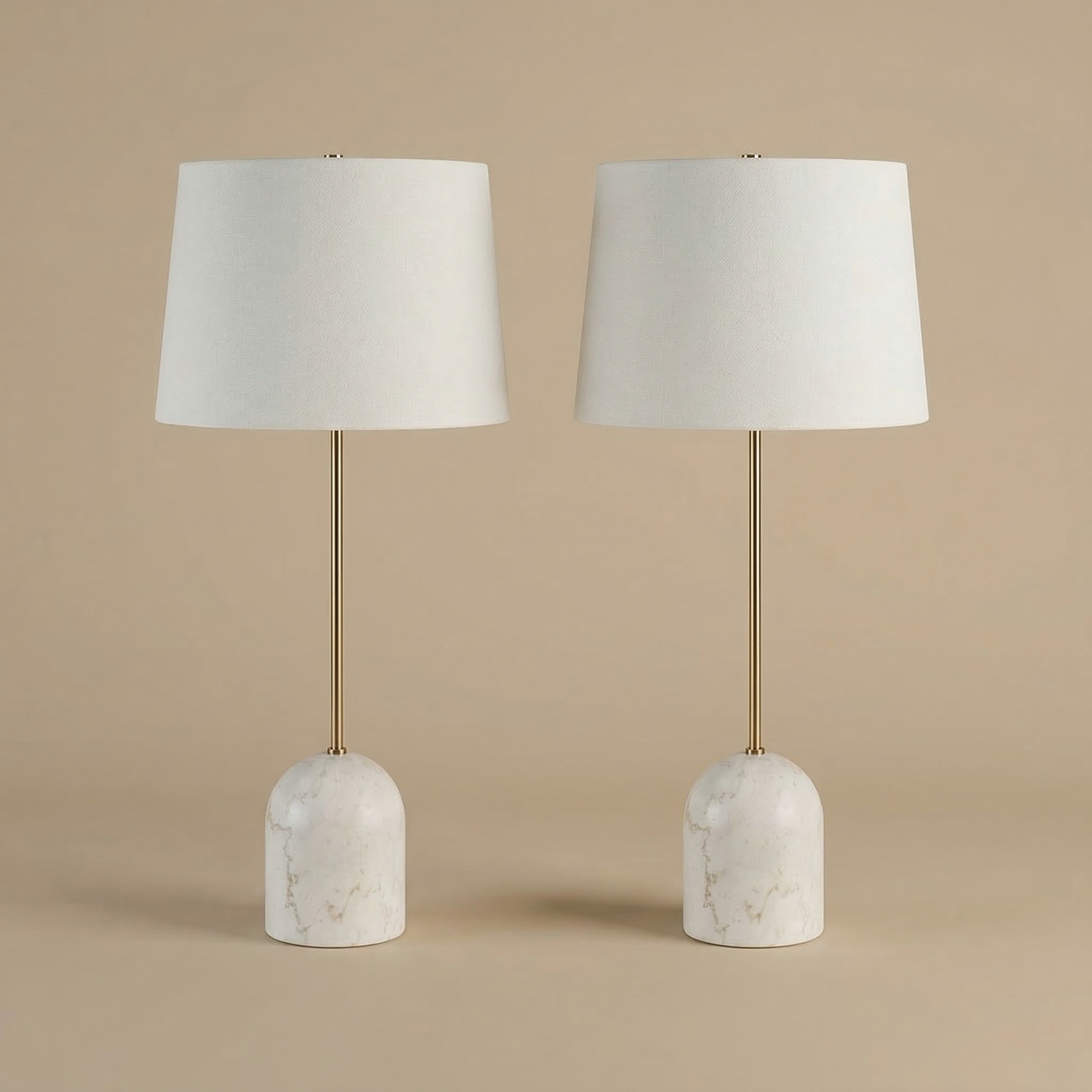 A pair of Celine table lamps featuring dome-shaped white marble bases, slender brass stems, and white linen shades.