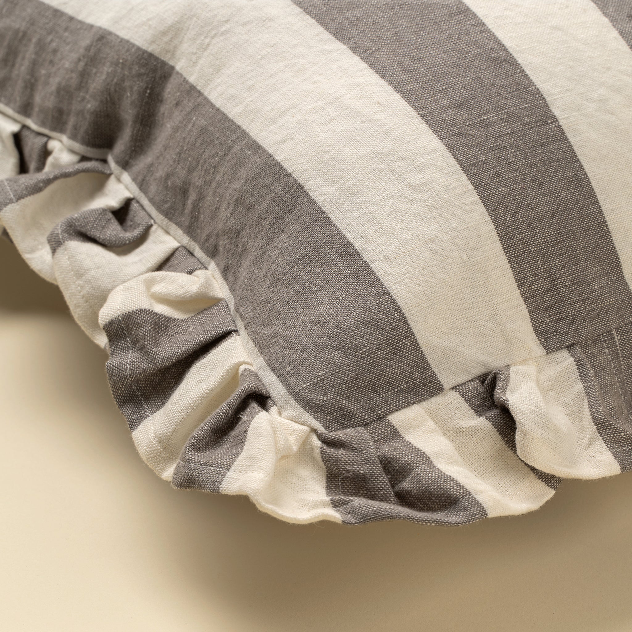 Close-up of a striped pillow with ruffled edges on a beige background