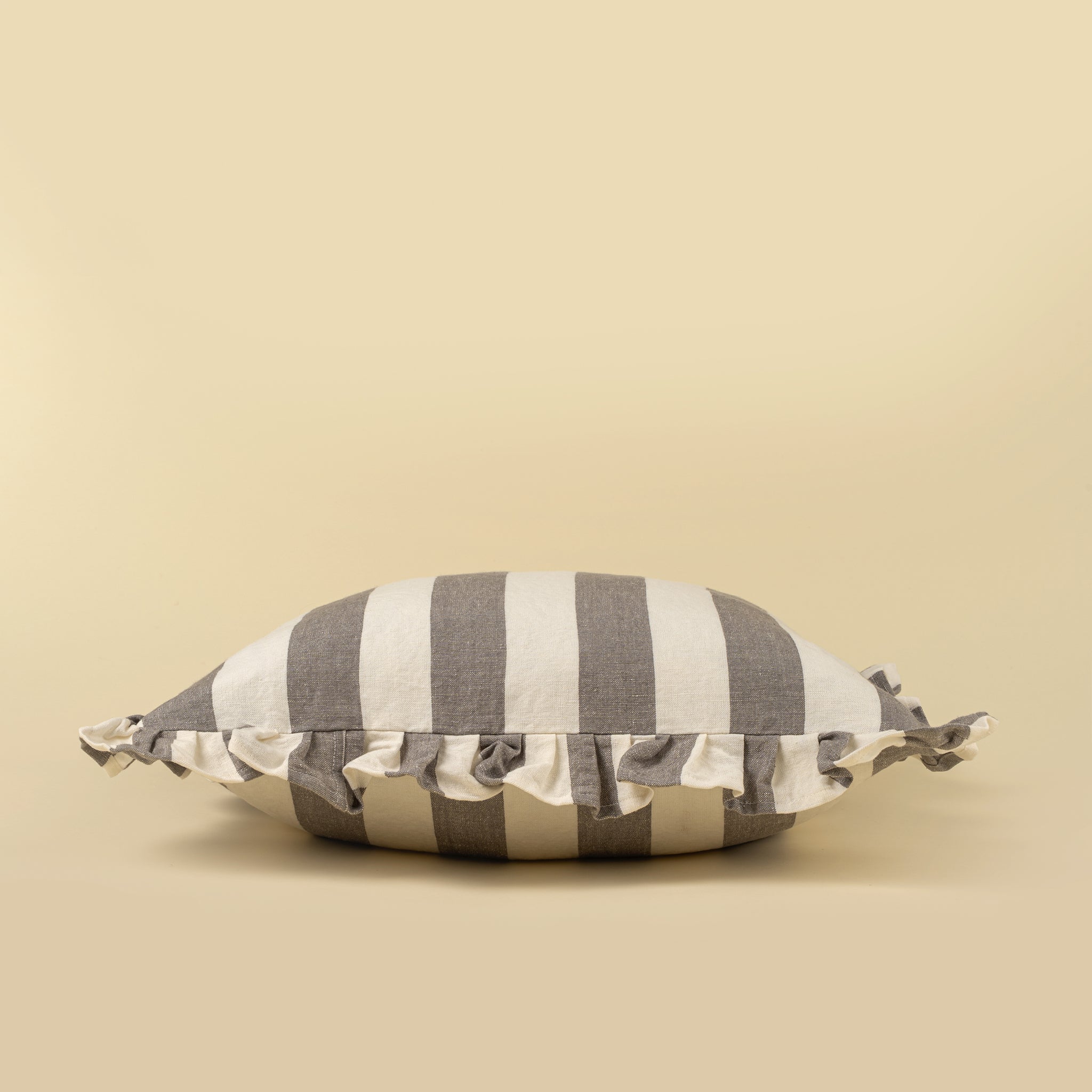 Striped pillow with ruffle trim on a beige background