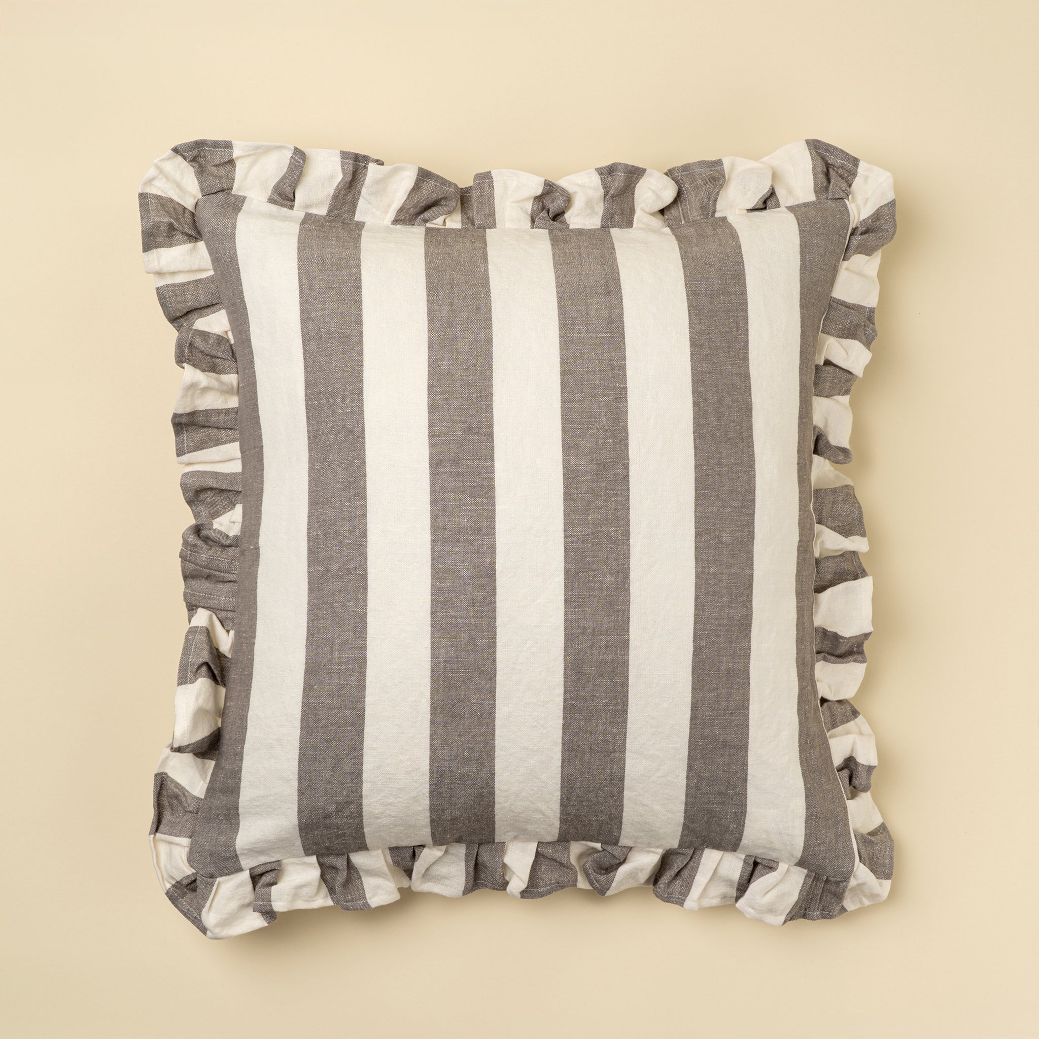 Striped pillow with ruffle trim on a beige background