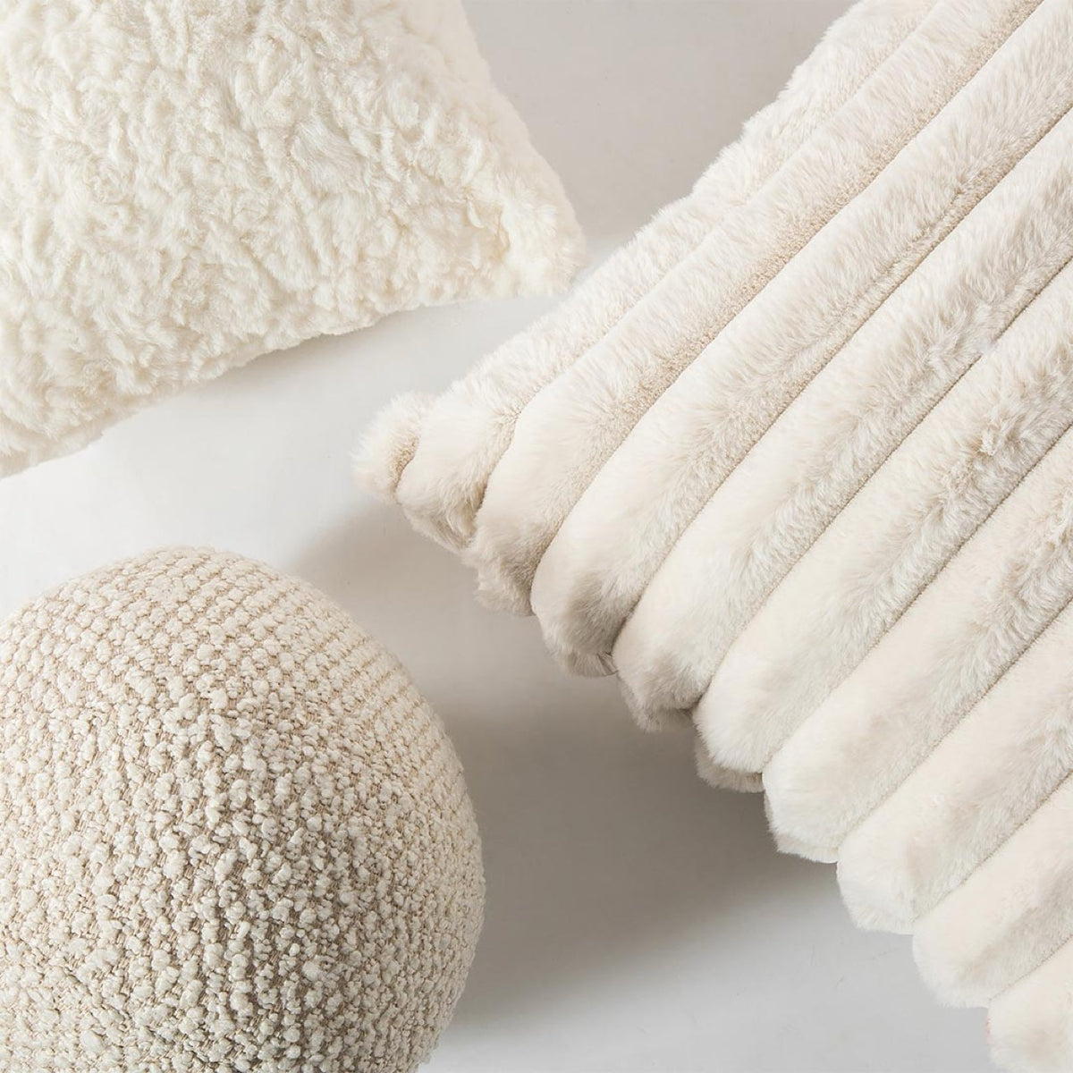 A grouping of the three Cloudline cushions showcasing the high-contrast medley of faux fur, curly-pile, and honeycomb weaves.