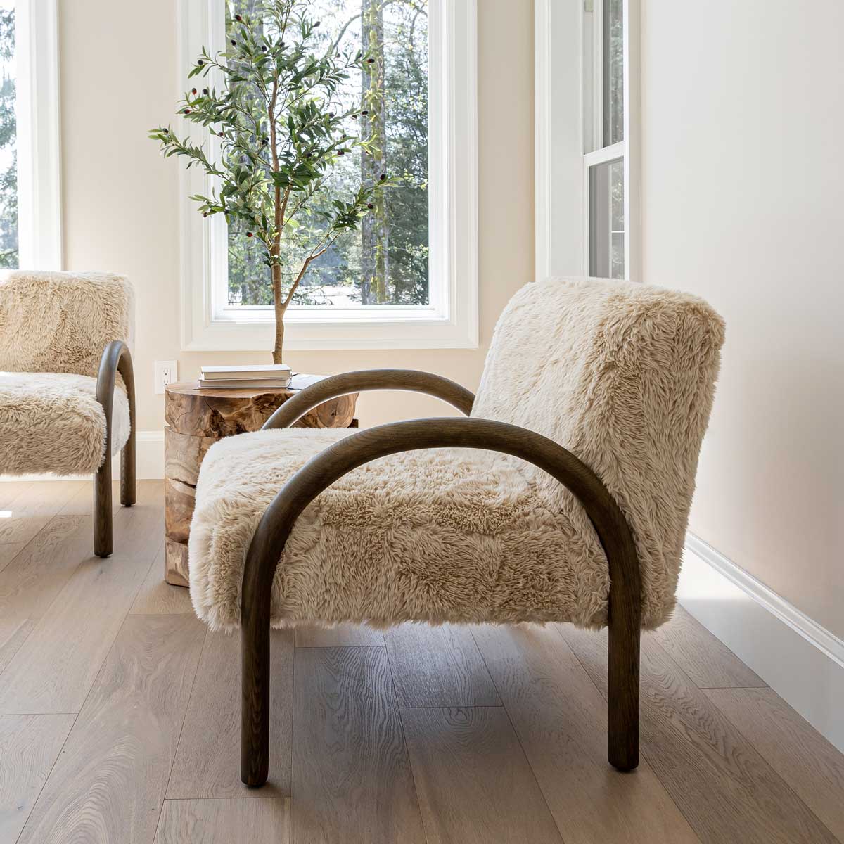 Wide lifestyle shot of the Coco chair in a contemporary living space with neutral tones and a rustic wood side table.