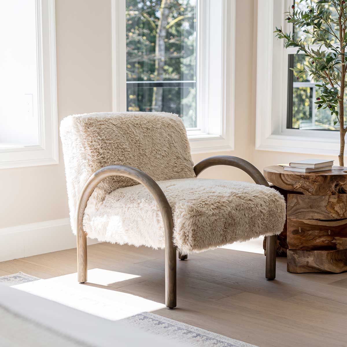 The Coco faux fur chair styled in a sun-drenched room by a large window, emphasizing its soft texture and organic form.