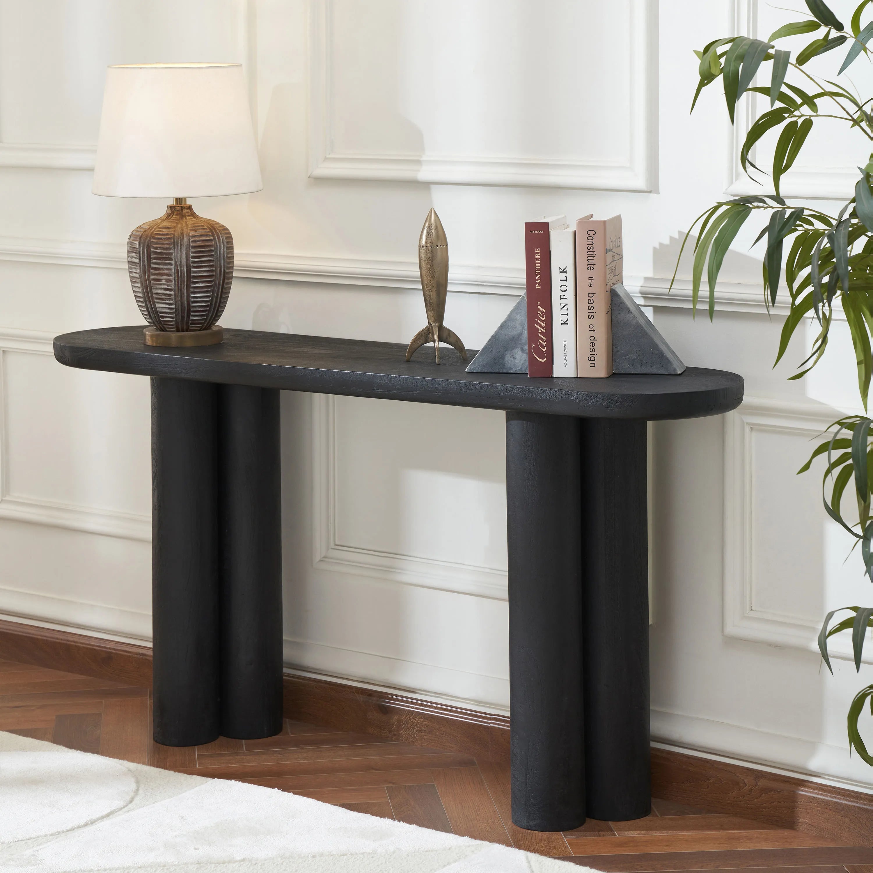 Black Daro console table styled in a modern hallway with a table lamp, books, and decorative objects.