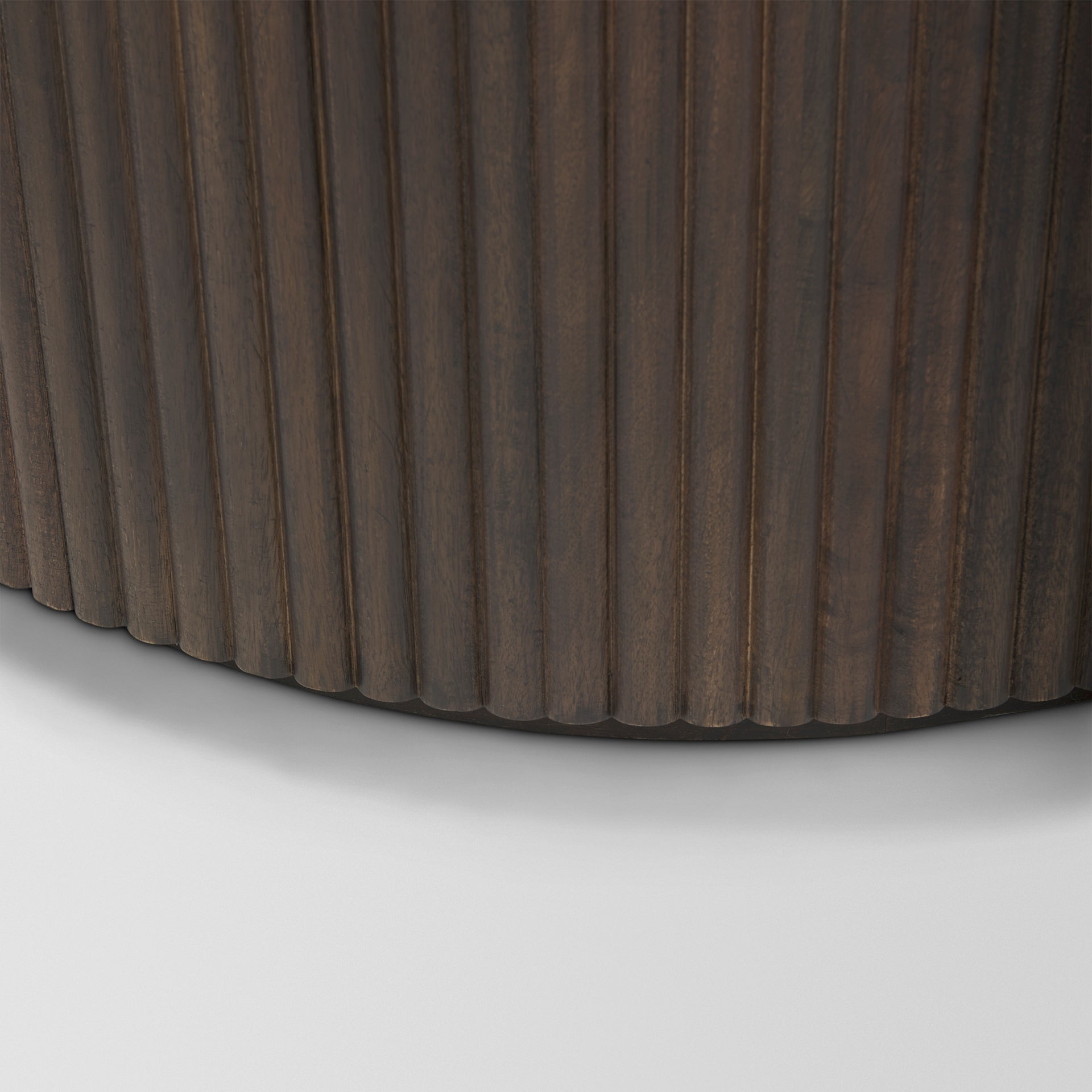 Close-up of the curved bottom edge and vertical fluted wood detailing on the dark brown Eleanor accent cabinet.