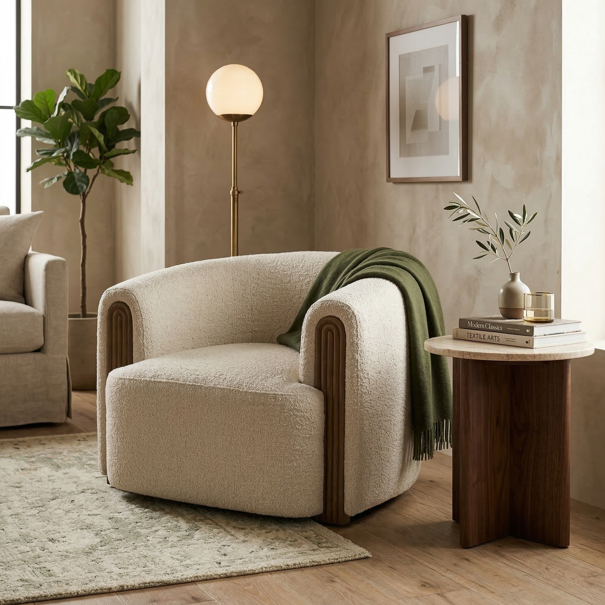 The cream Elodie barrel chair styled in a contemporary living room with a green throw, walnut side table, and textured rug.