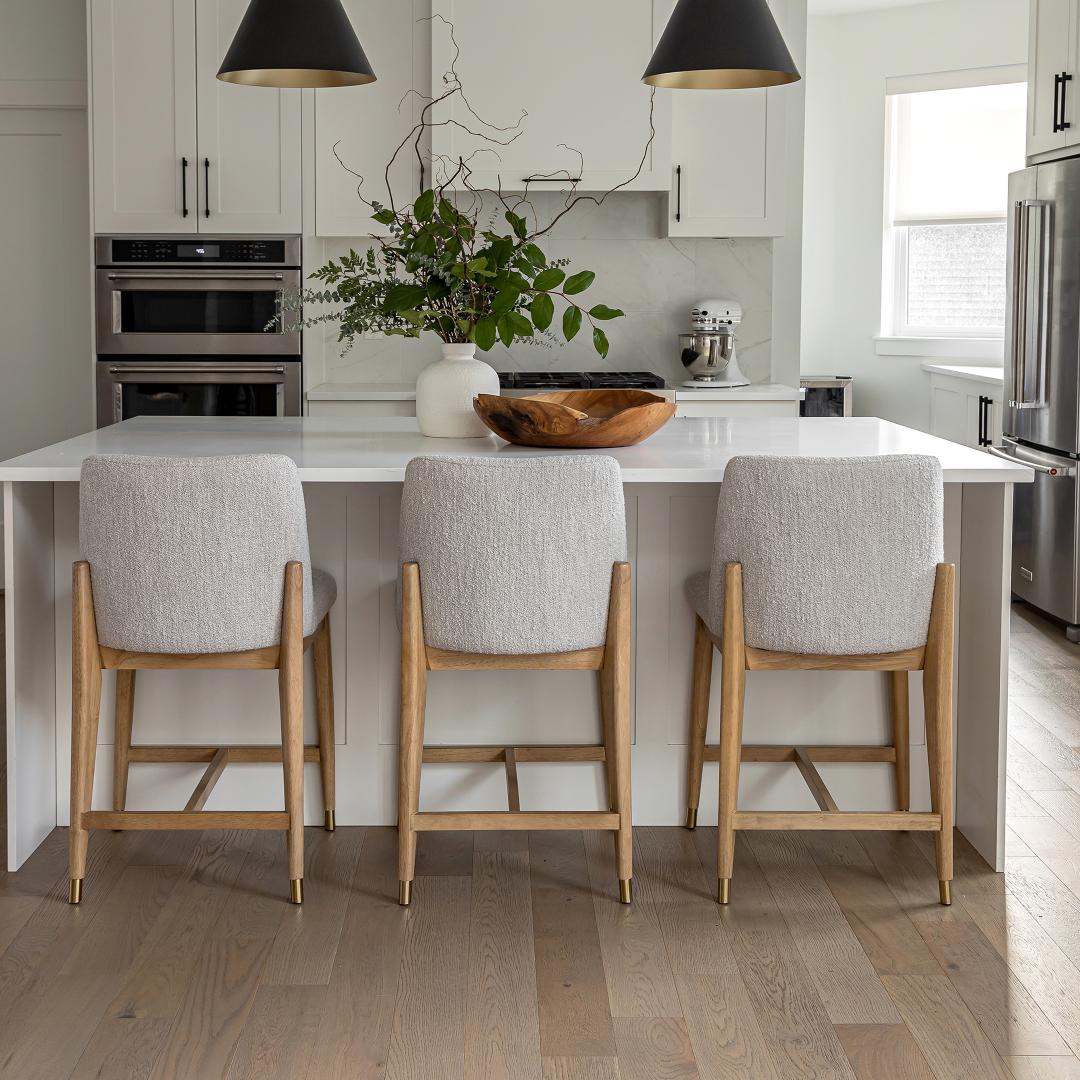 Three Fawcett taupe bouclé counter stools styled at a white quartz kitchen island in a bright, contemporary home.