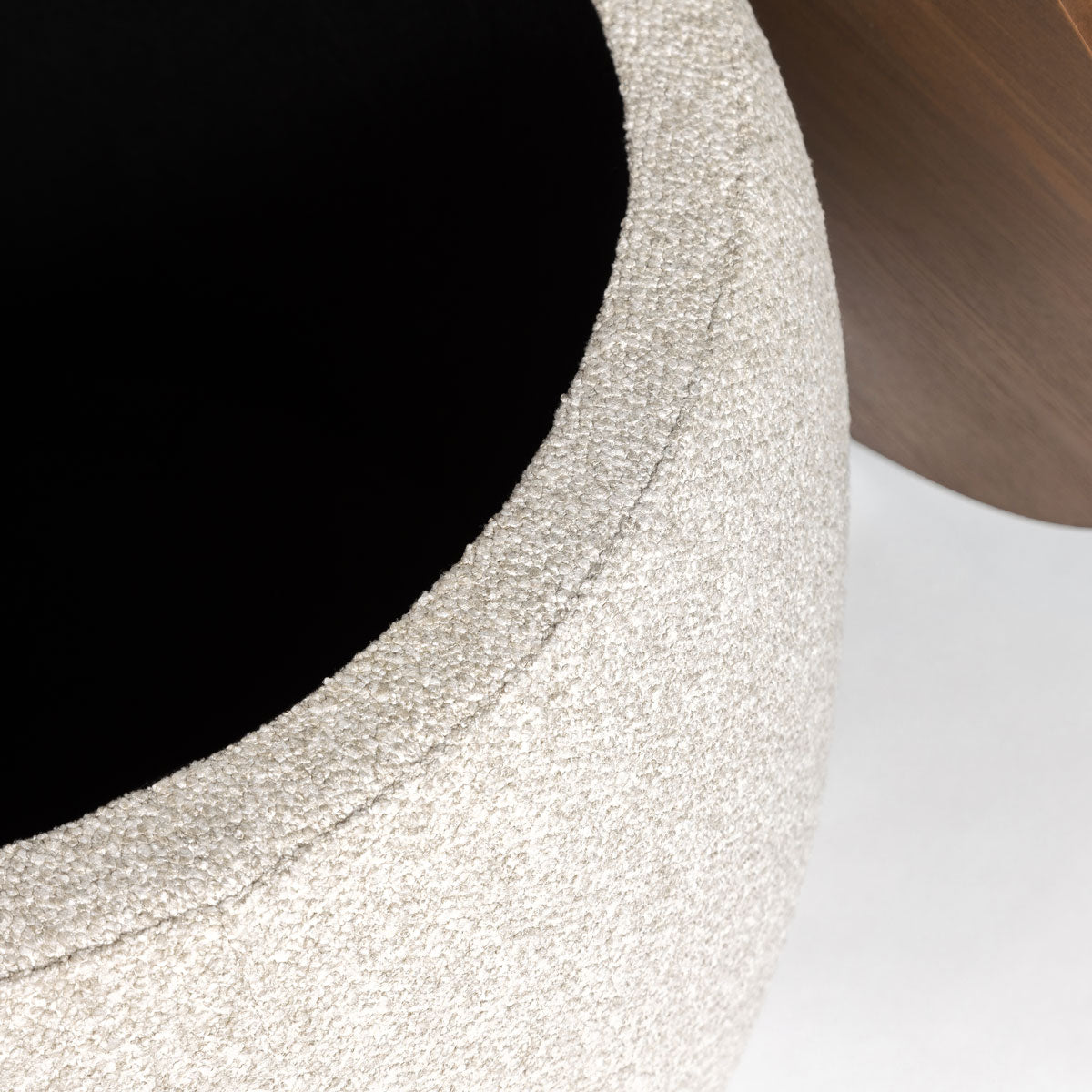 Macro close-up of the Haven Storage Ottoman showing the high-quality, nubby cream bouclé upholstery and the edge of the wood lid.