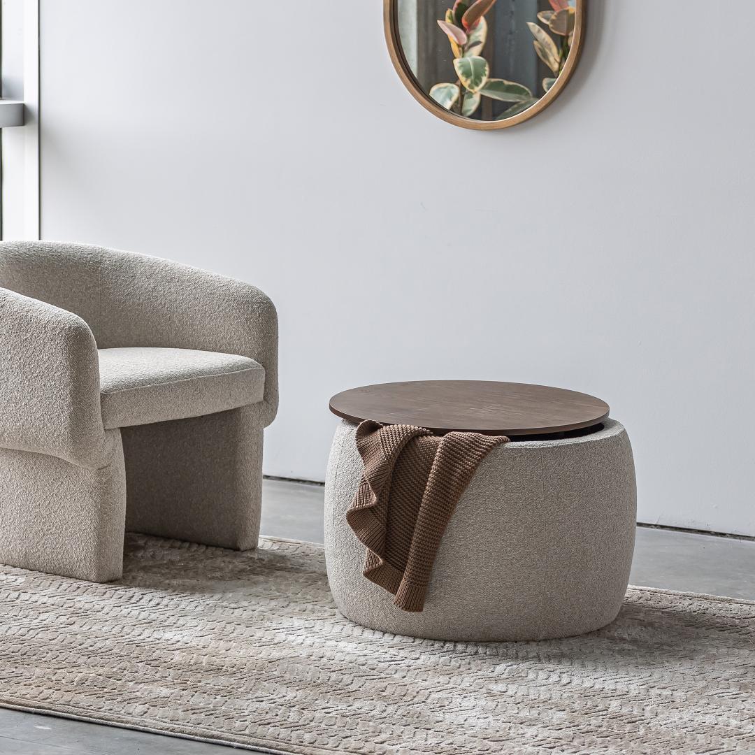 The Haven Storage Ottoman styled as a coffee table next to a bouclé lounge chair on a textured neutral rug.