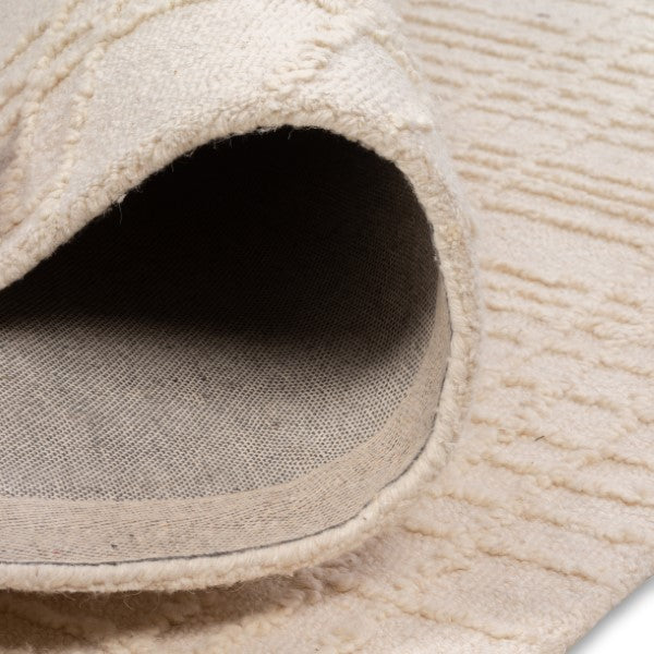 Rolled edge of the Hayes cream grid rug showcasing its soft textured top pile and durable woven backing