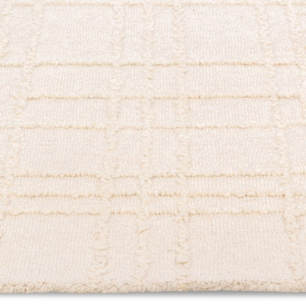 Macro close-up of the raised tufted geometric grid pattern and soft cream pile on the Hayes textured area rug