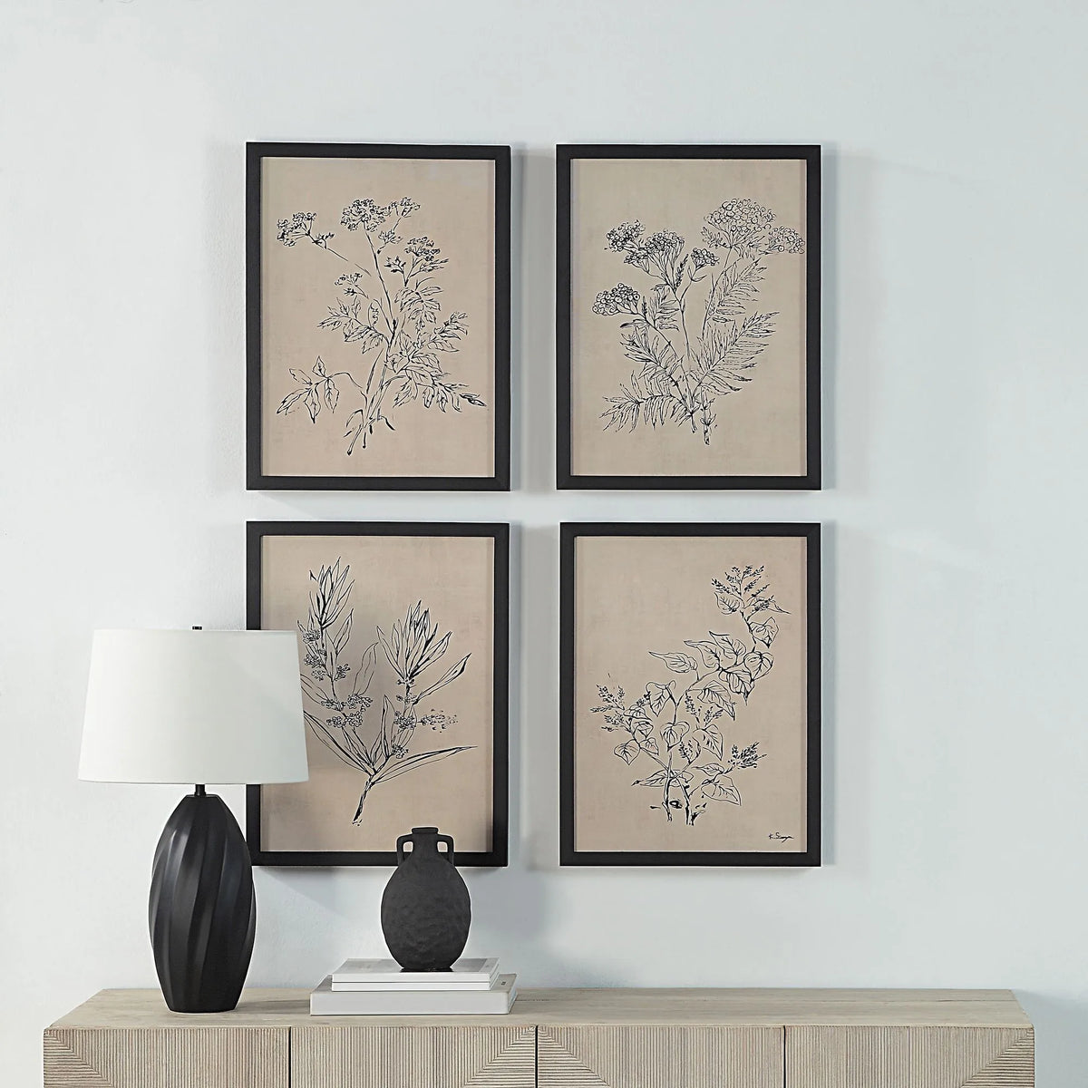 Herbarium Noir botanical wall art set hanging on a white wall above a wooden console table with a black lamp for modern home decor