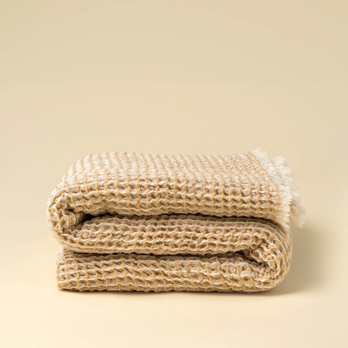 Folded beige textured blanket on a beige background