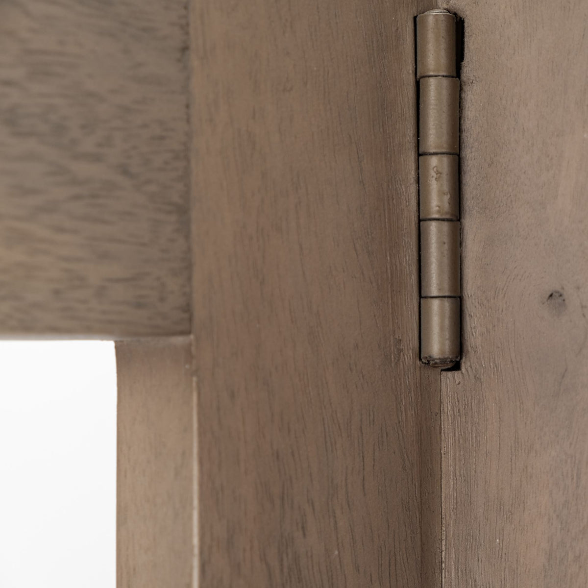 Macro detail of the antiqued metal hinge that connects the folding wooden frames of the Kade geometric shelving unit.
