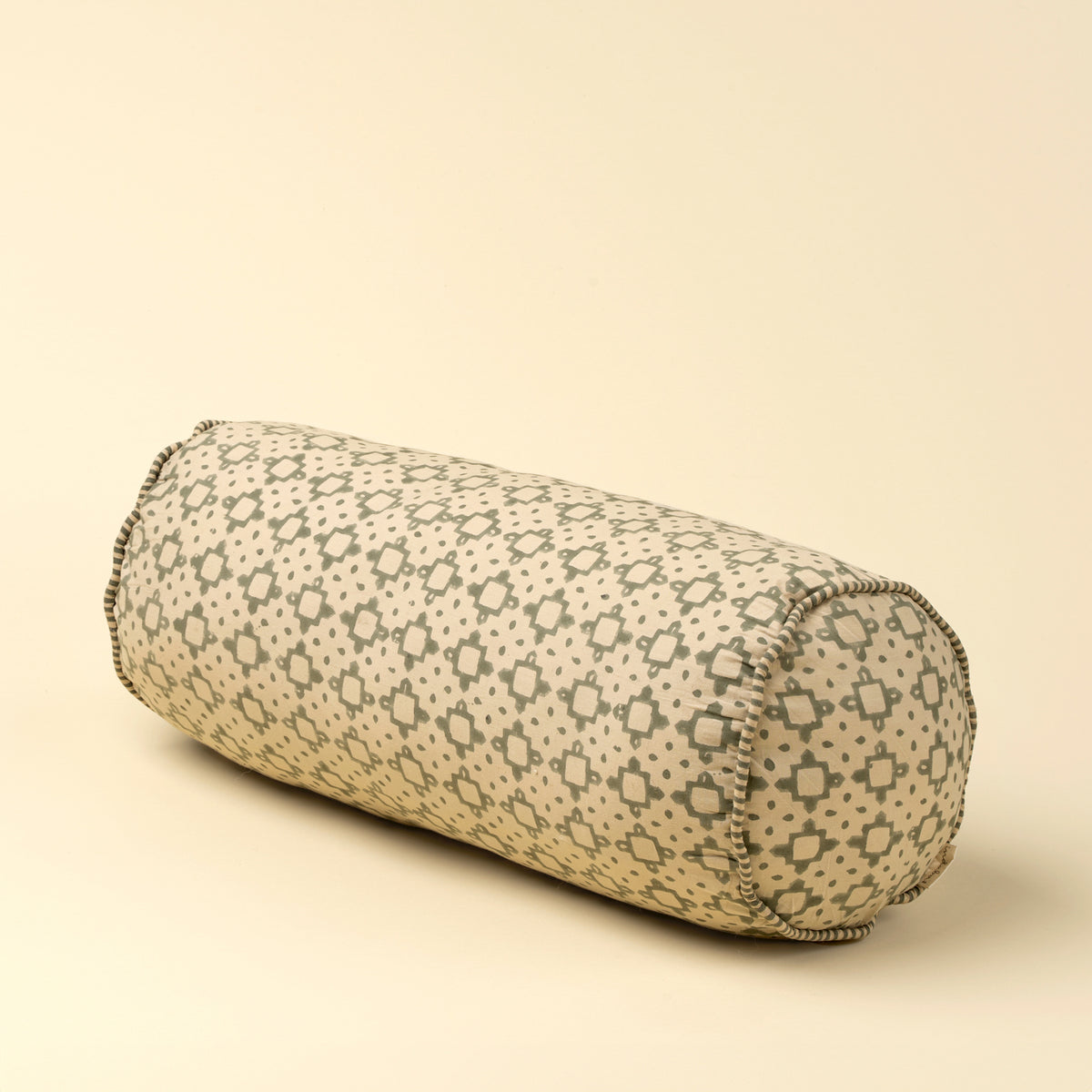 cylindrical pillow with geometric pattern on a beige background