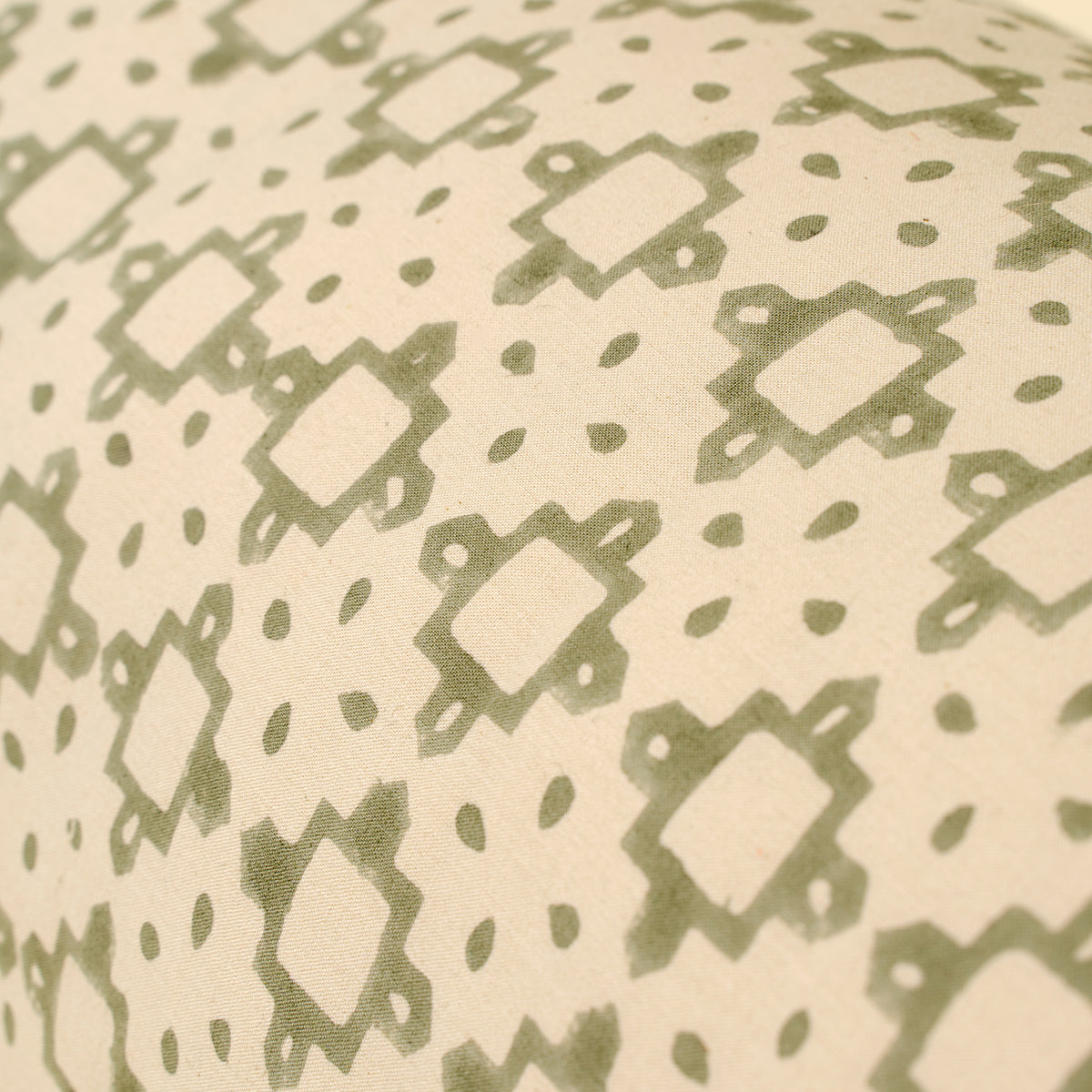 Close-up of a fabric with a green geometric pattern on a beige background