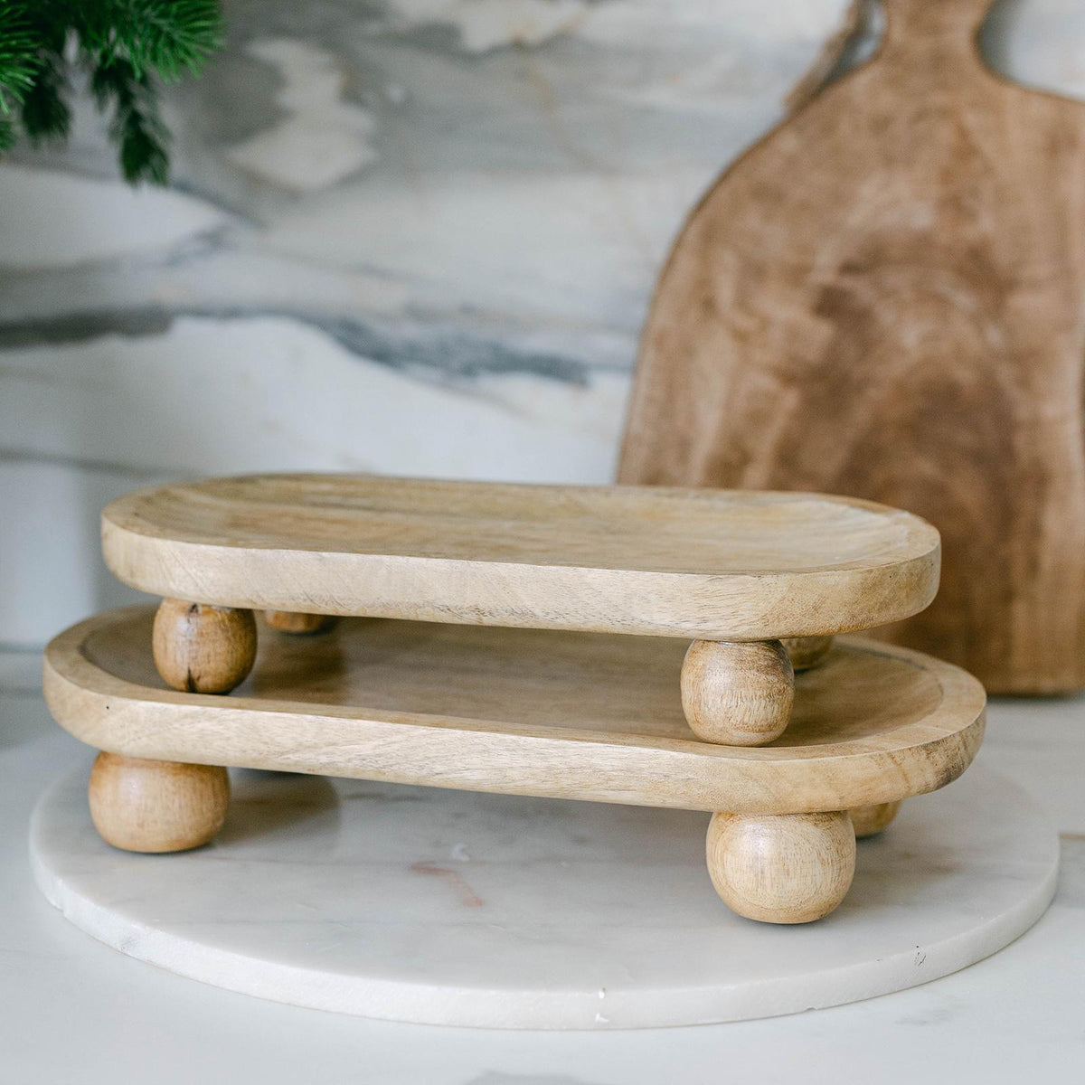 Two-tiered wooden stand on a marble surface with a blurred background