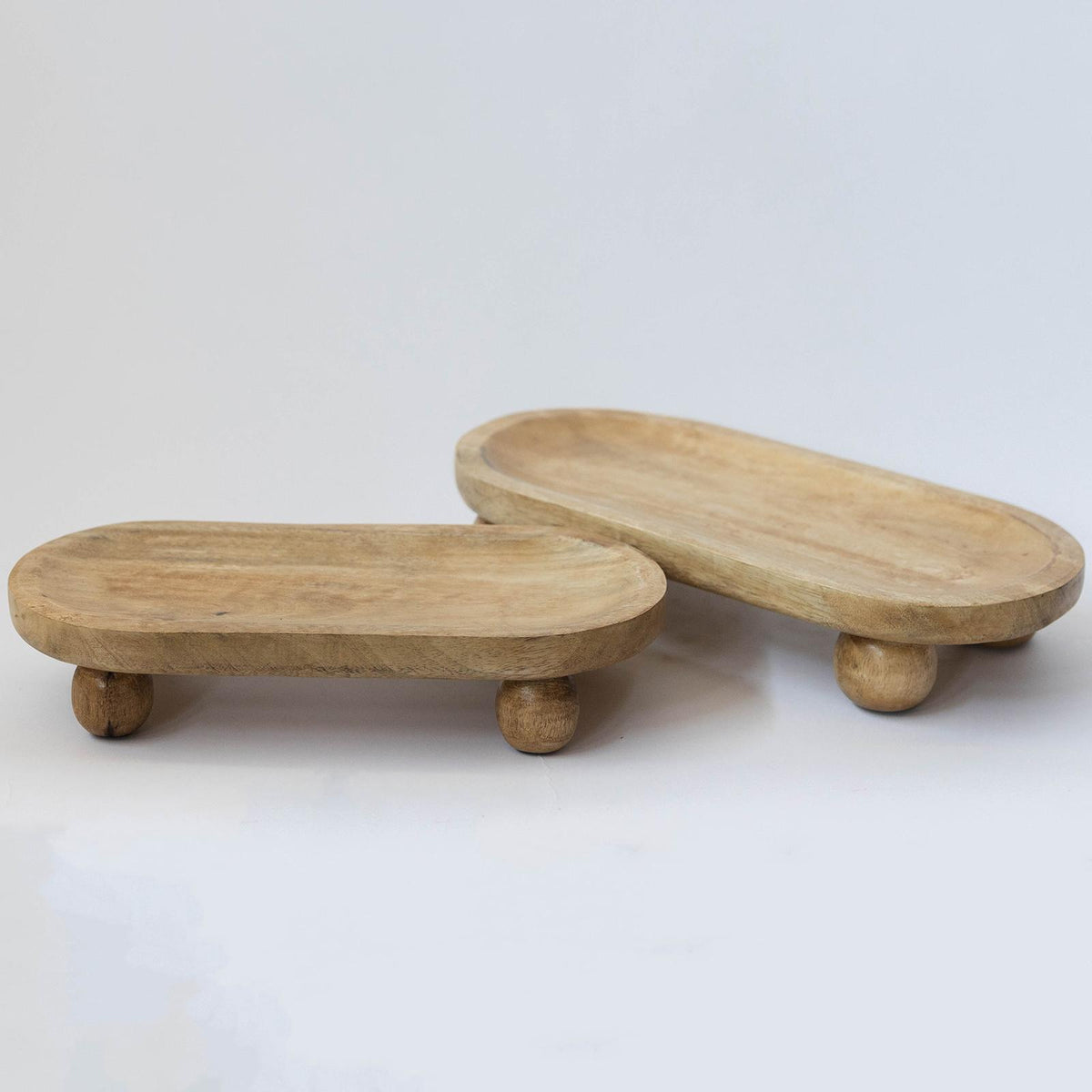 Two wooden footstools with round tops and legs on a white background