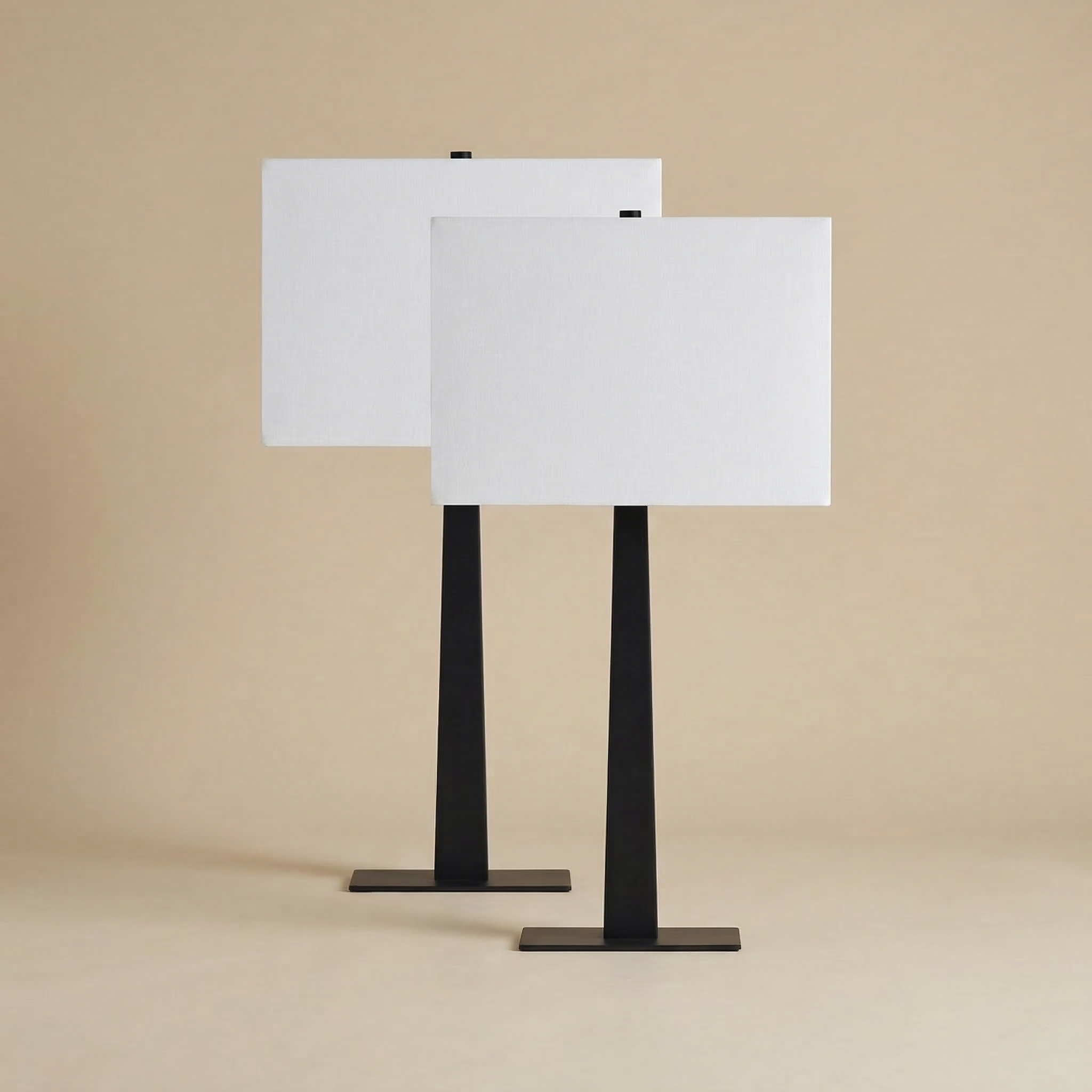 A pair of Kyler table lamps featuring tapering matte black square bases and large white rectangular linen shades.