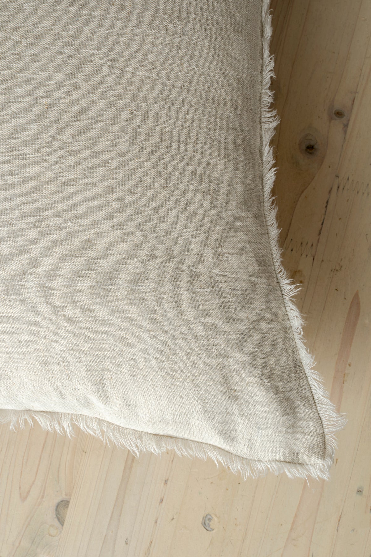 Macro close-up of the Lina linen pillow showcasing the breathable fabric and the delicate frayed fringe edge
