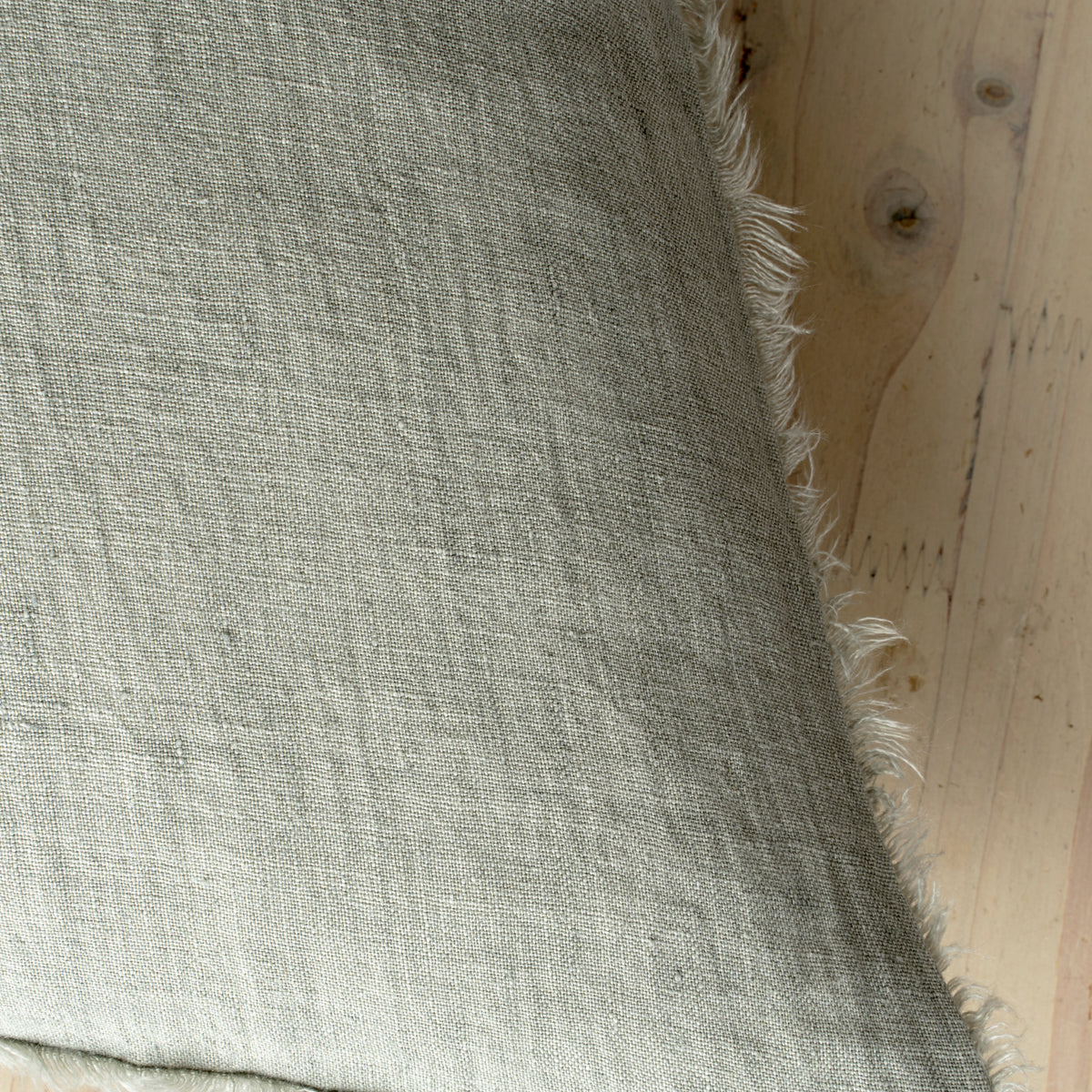 Macro close-up of the Lina linen pillow showcasing the breathable fabric and the delicate frayed fringe edge