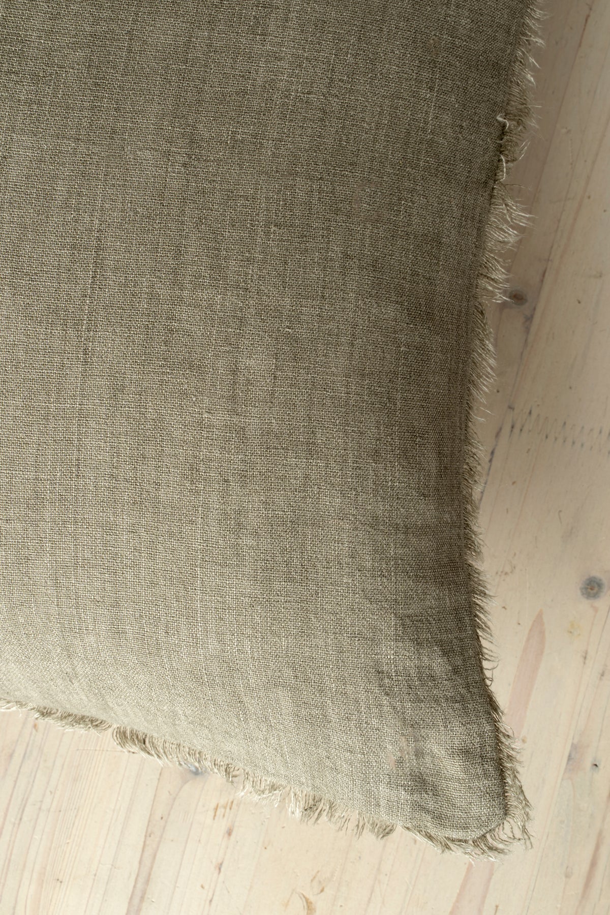 Macro close-up of the Lina linen pillow showcasing the breathable fabric and the delicate frayed fringe edge