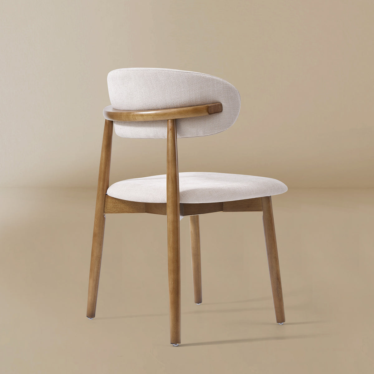 Back side view of the Linen Ash Wood Dining Side Chairs with curved upholstered backs and ash wood frames, shown in a neutral studio setting