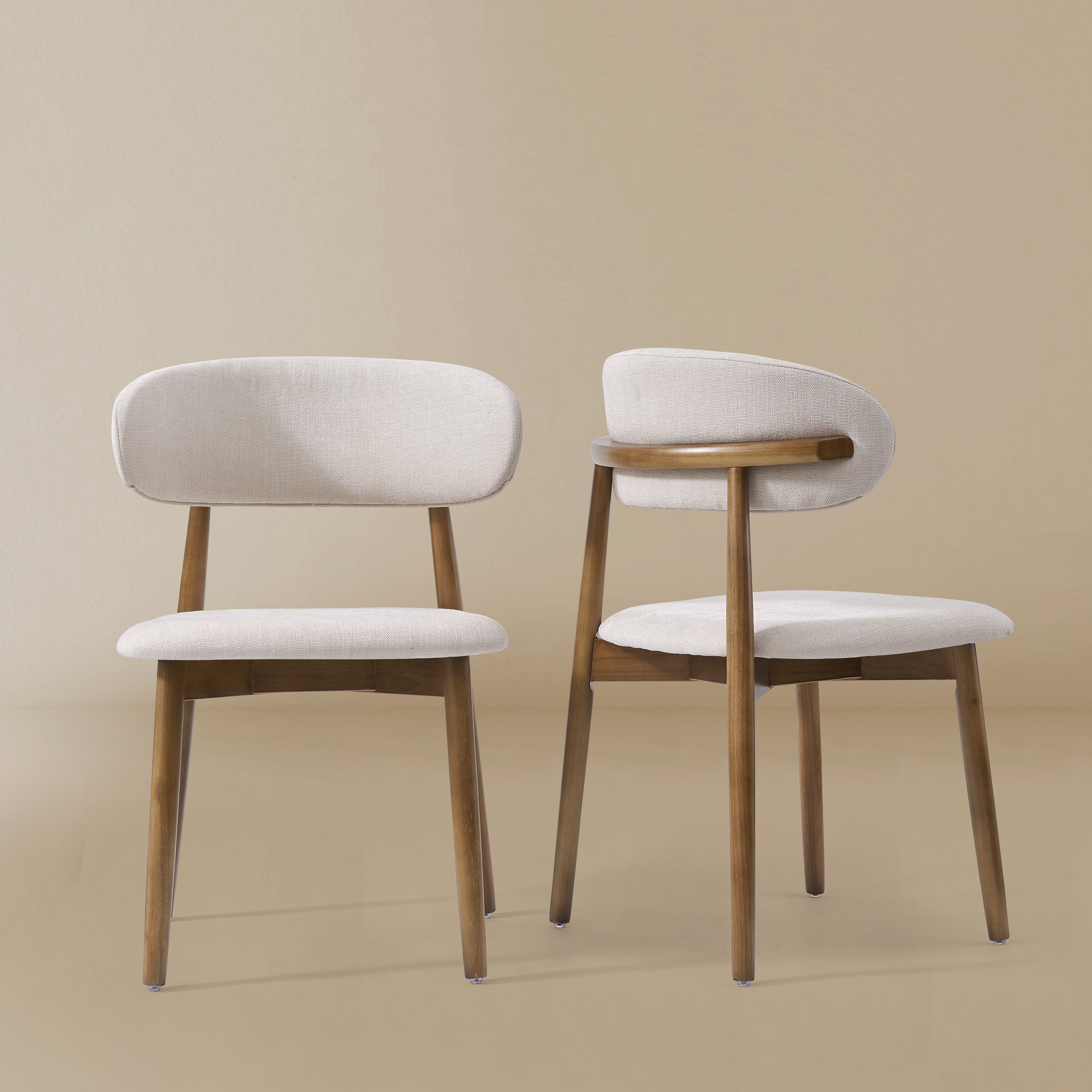 Two Linen Ash Wood Dining Side Chairs with curved upholstered backs and ash wood frames, shown in a neutral studio setting