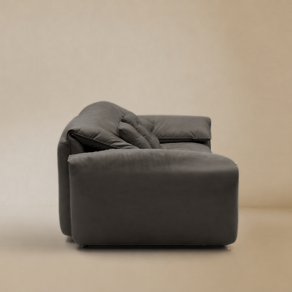 Side view of gray elephant ear sofa on a beige background.