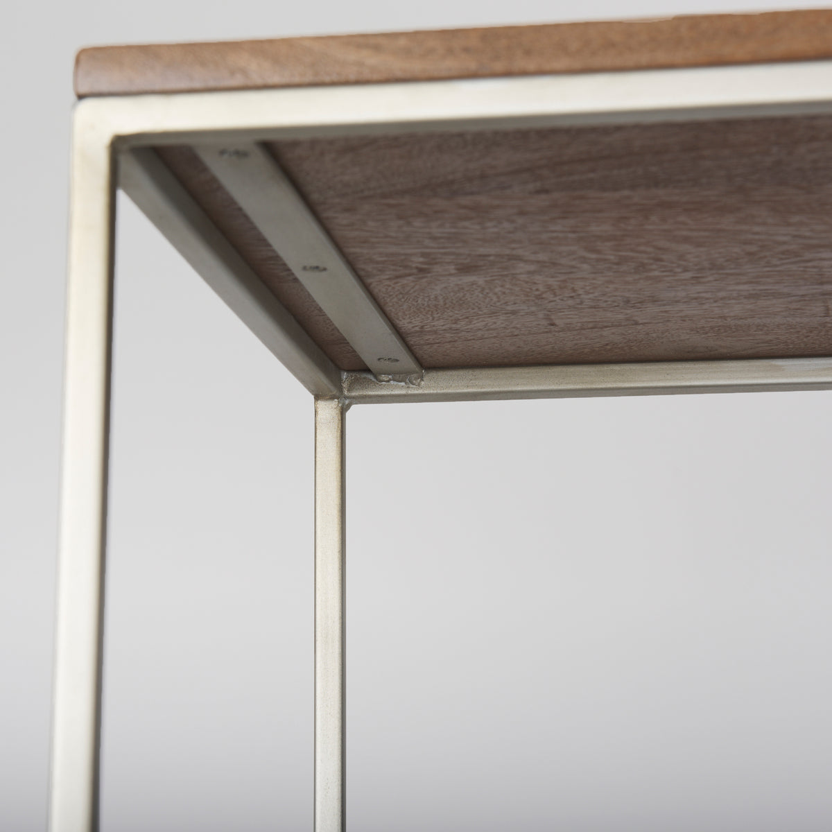 Close-up view of the underside of a wooden shelf and the supporting metal frame construction on the Maddox shelving unit.