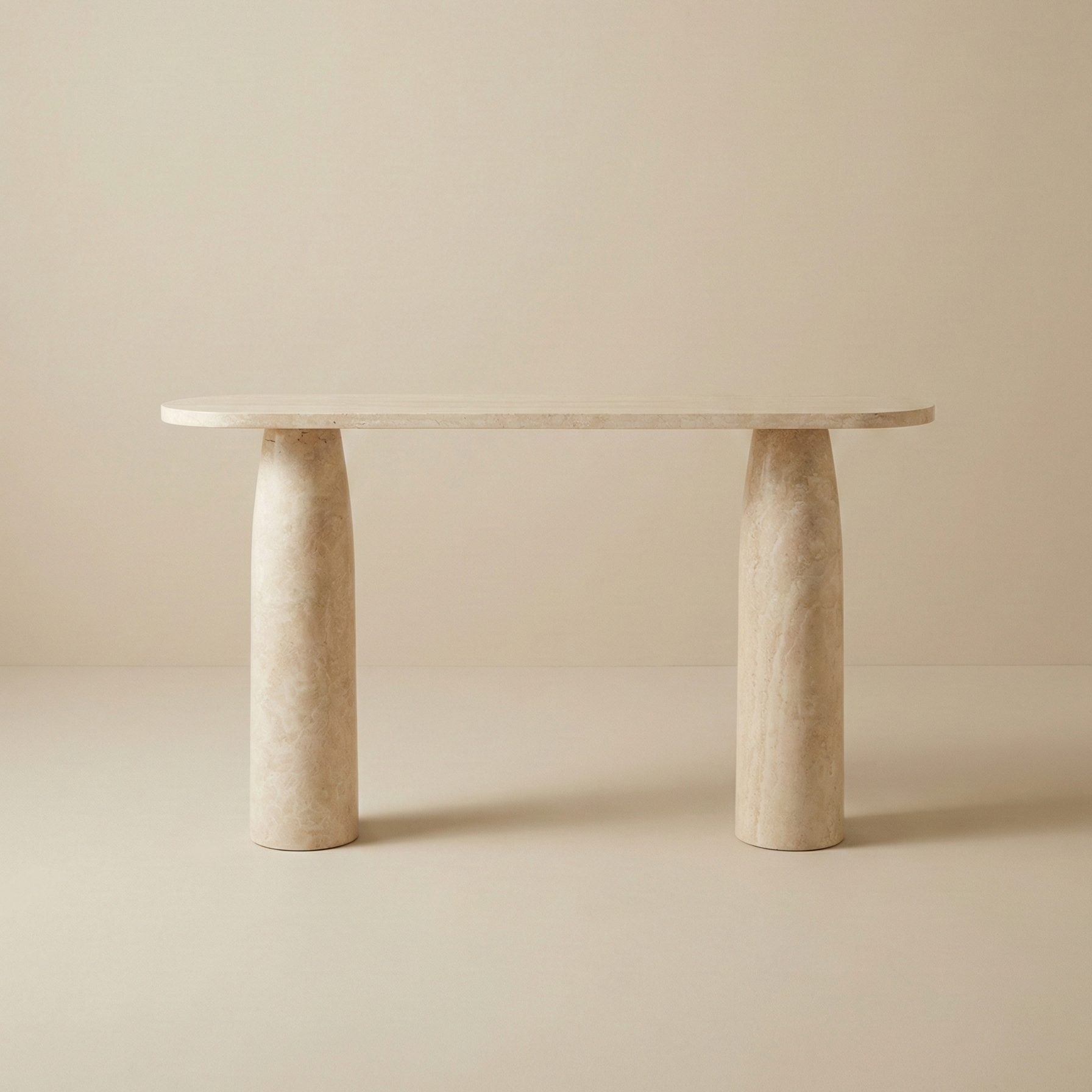 Front view of the Maelis console table featuring a pill-shaped natural travertine top supported by two sturdy cylindrical stone column legs.