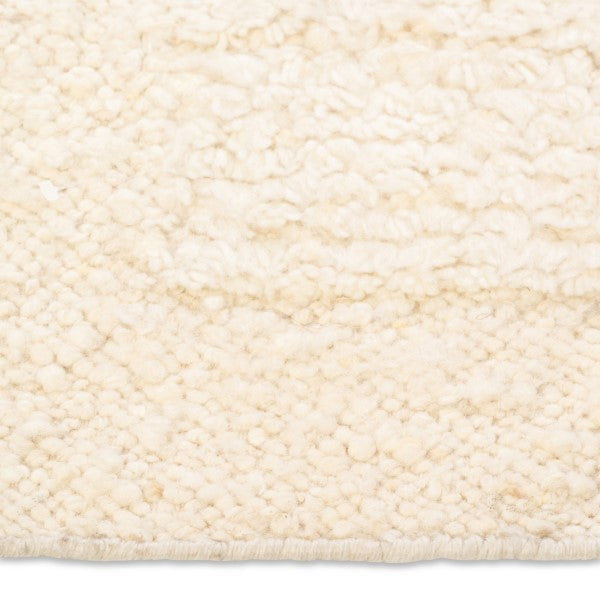 Macro detail of the Maeve hand-woven rug surface highlighting the ultra-textured, chunky nubby wool pile in warm cream