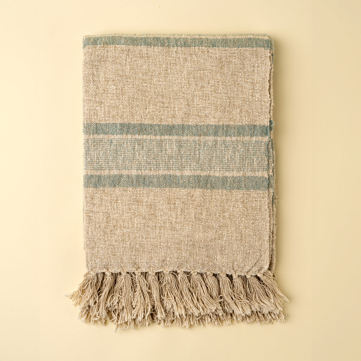 Textured throw blanket with fringes on a beige background
