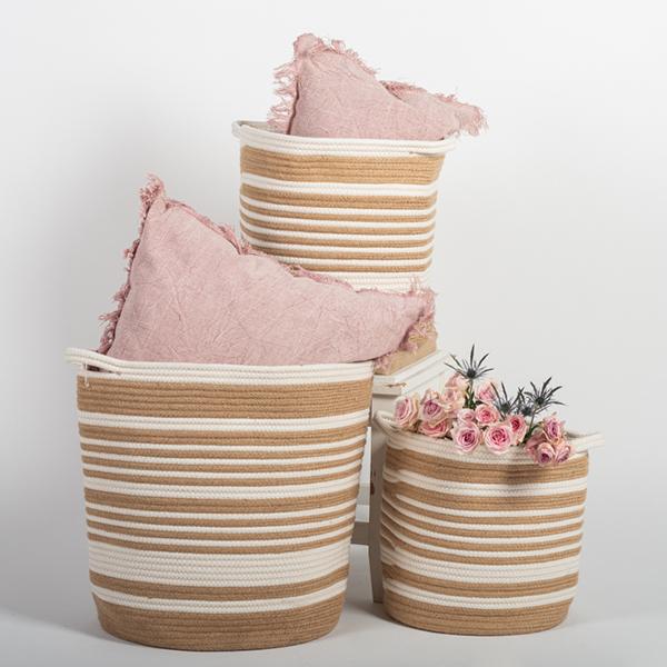 Set of striped woven baskets with pink pillows and flowers on a light background