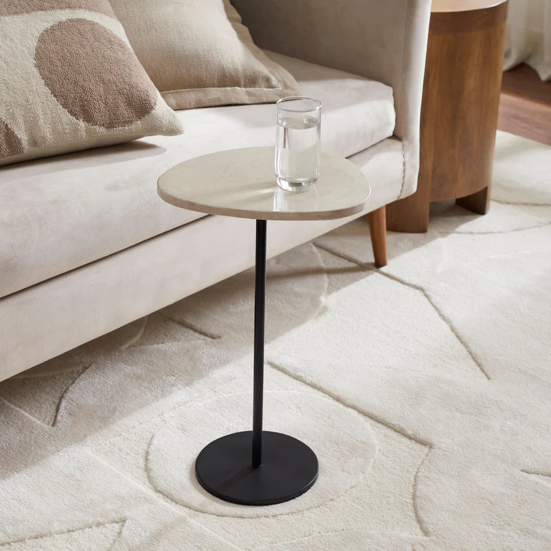 Small round side table with a black base and wooden top in a living room setting.