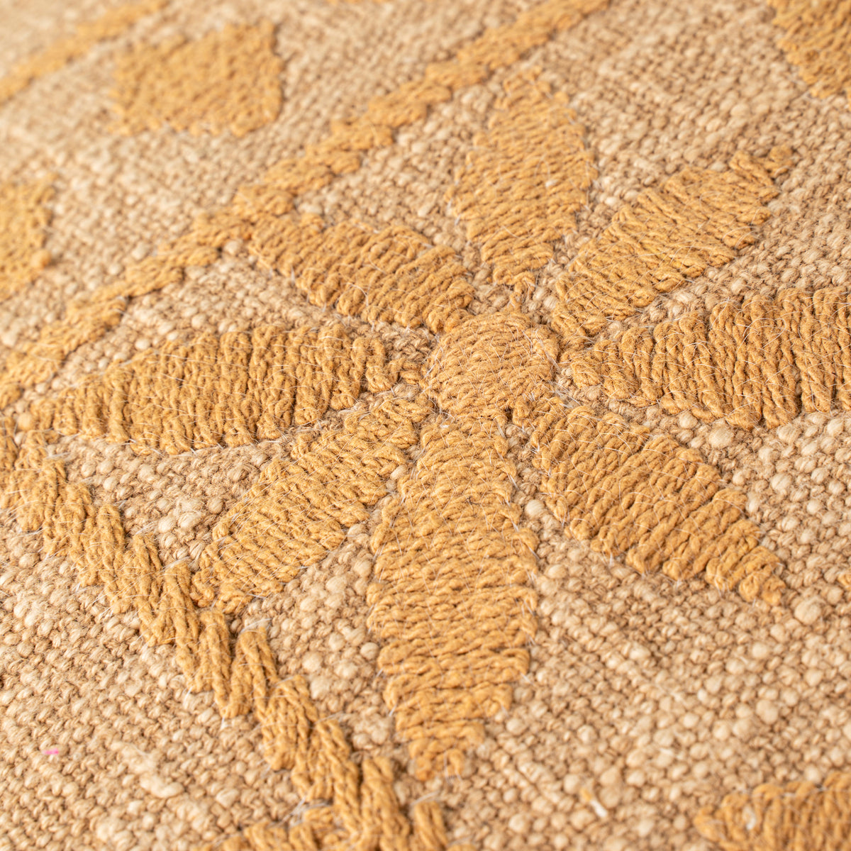 Close-up of a textured beige and brown carpet with a geometric pattern