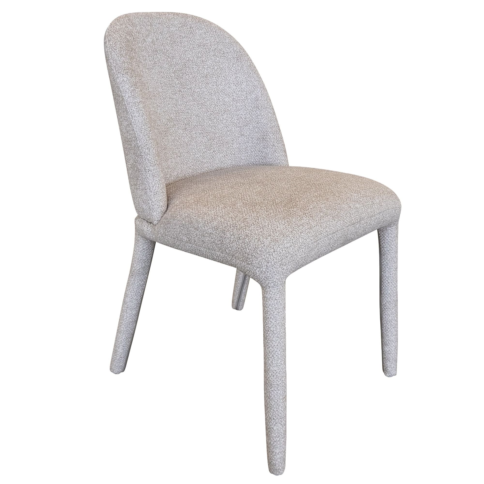 Angled view of the beige Myla dining chair highlighting its continuous upholstered silhouette and plush textured fabric.