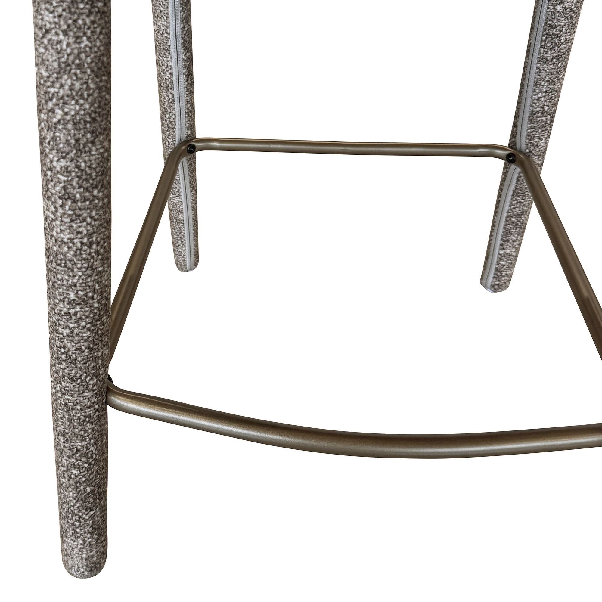 Close-up detail of the Myla counter stool highlighting the speckled light grey fabric and the curved antique brass metal footrest.