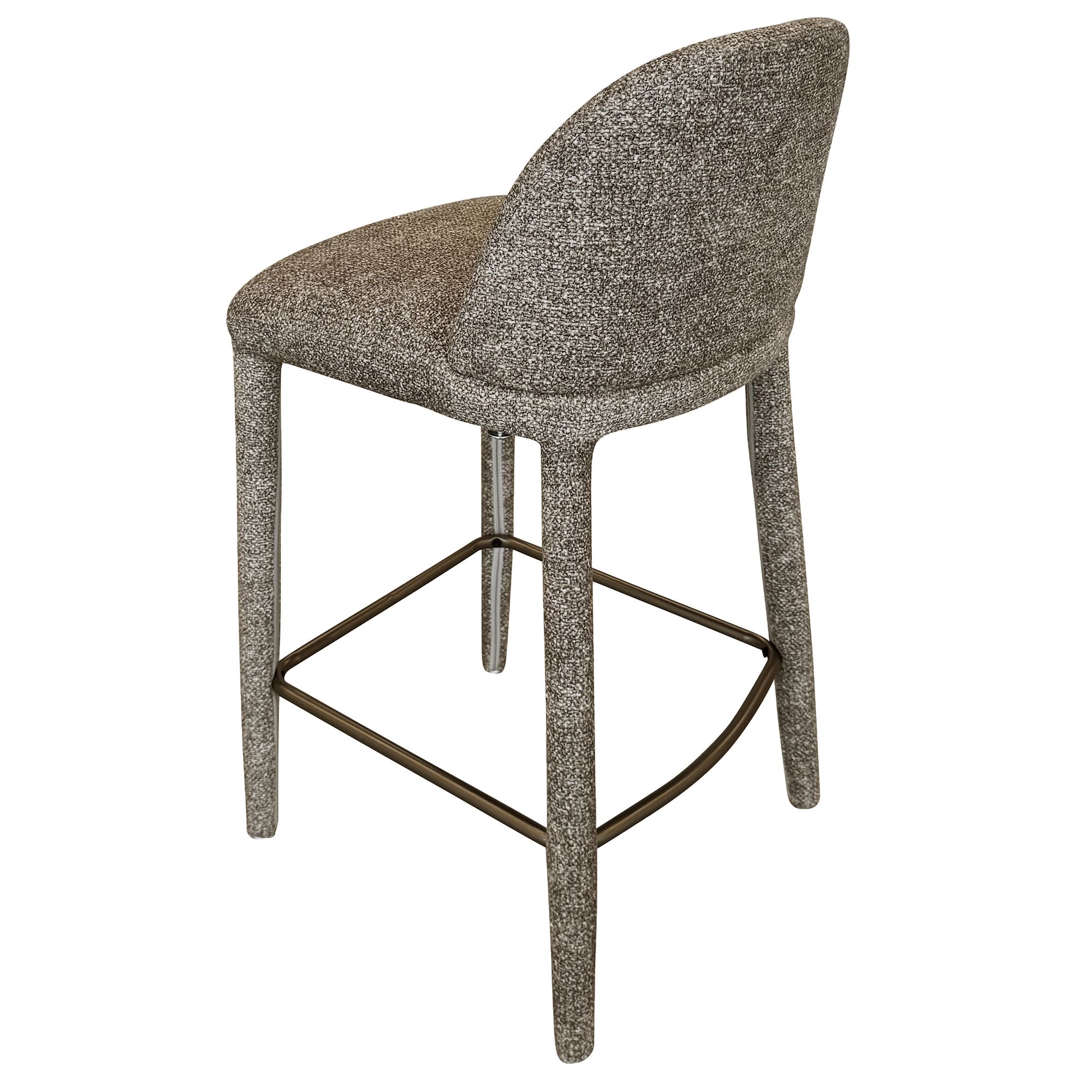 Angled back view of the light grey Myla counter stool showing its continuous upholstered silhouette and brass footrest